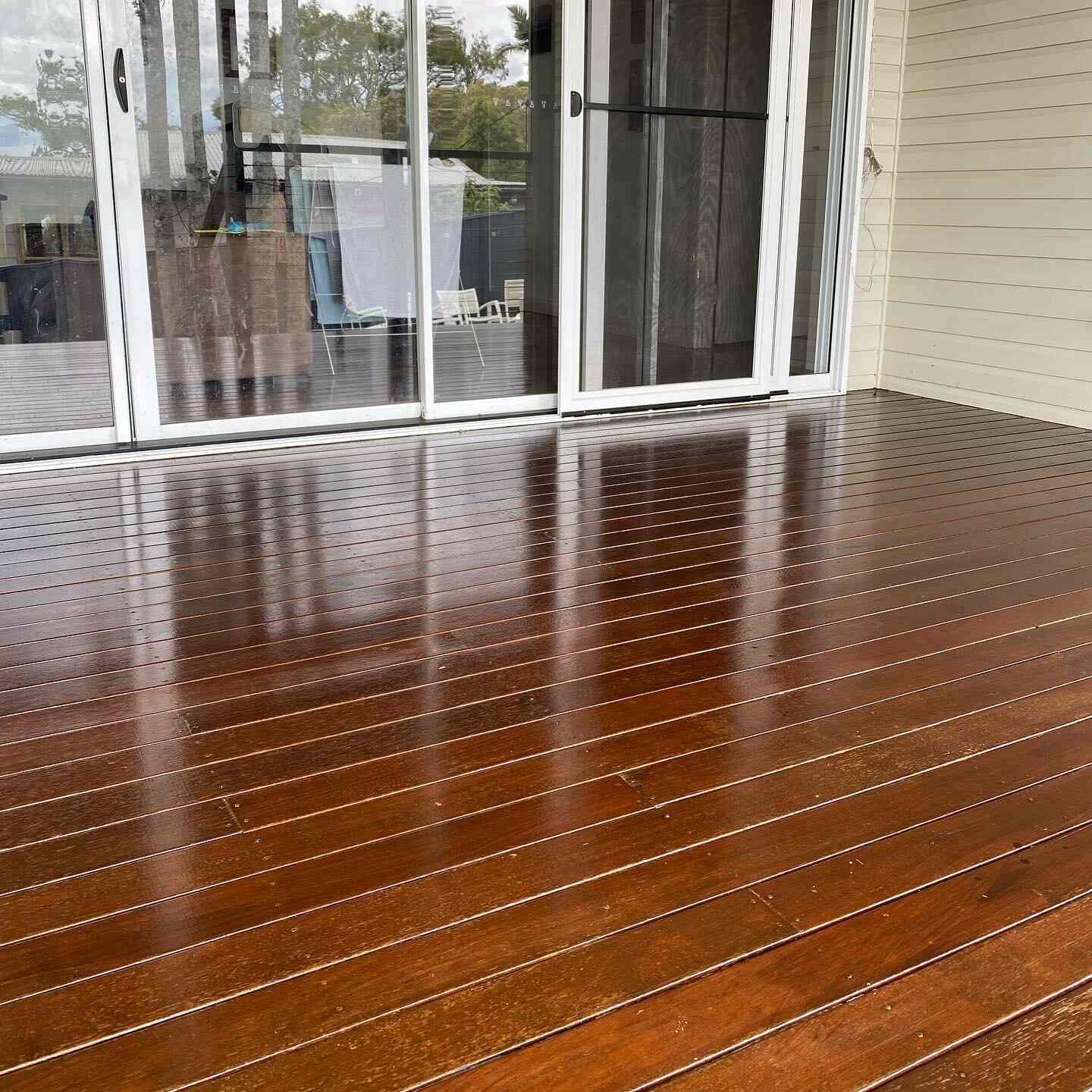Glossy oiled timber deck outside glass sliding doors