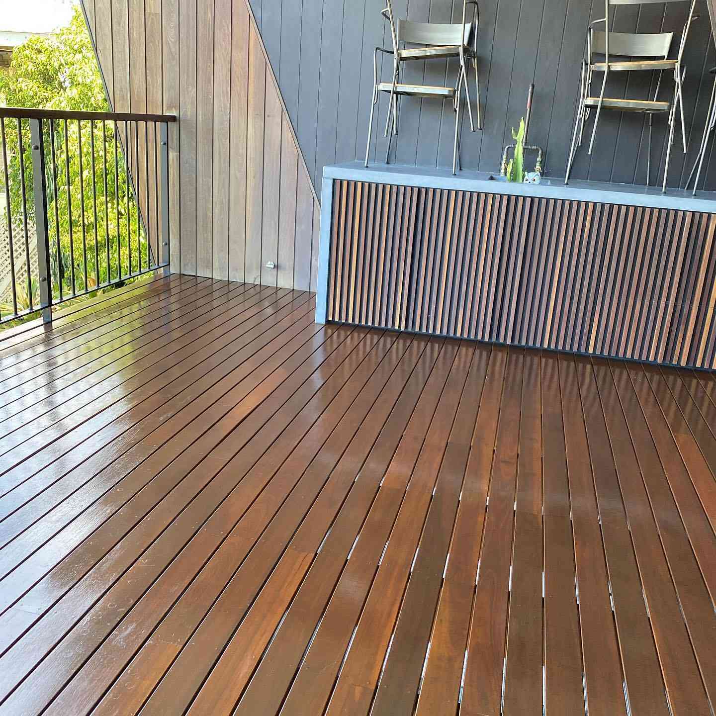Glossy oiled timber deck with black balustrade and a slatted bench