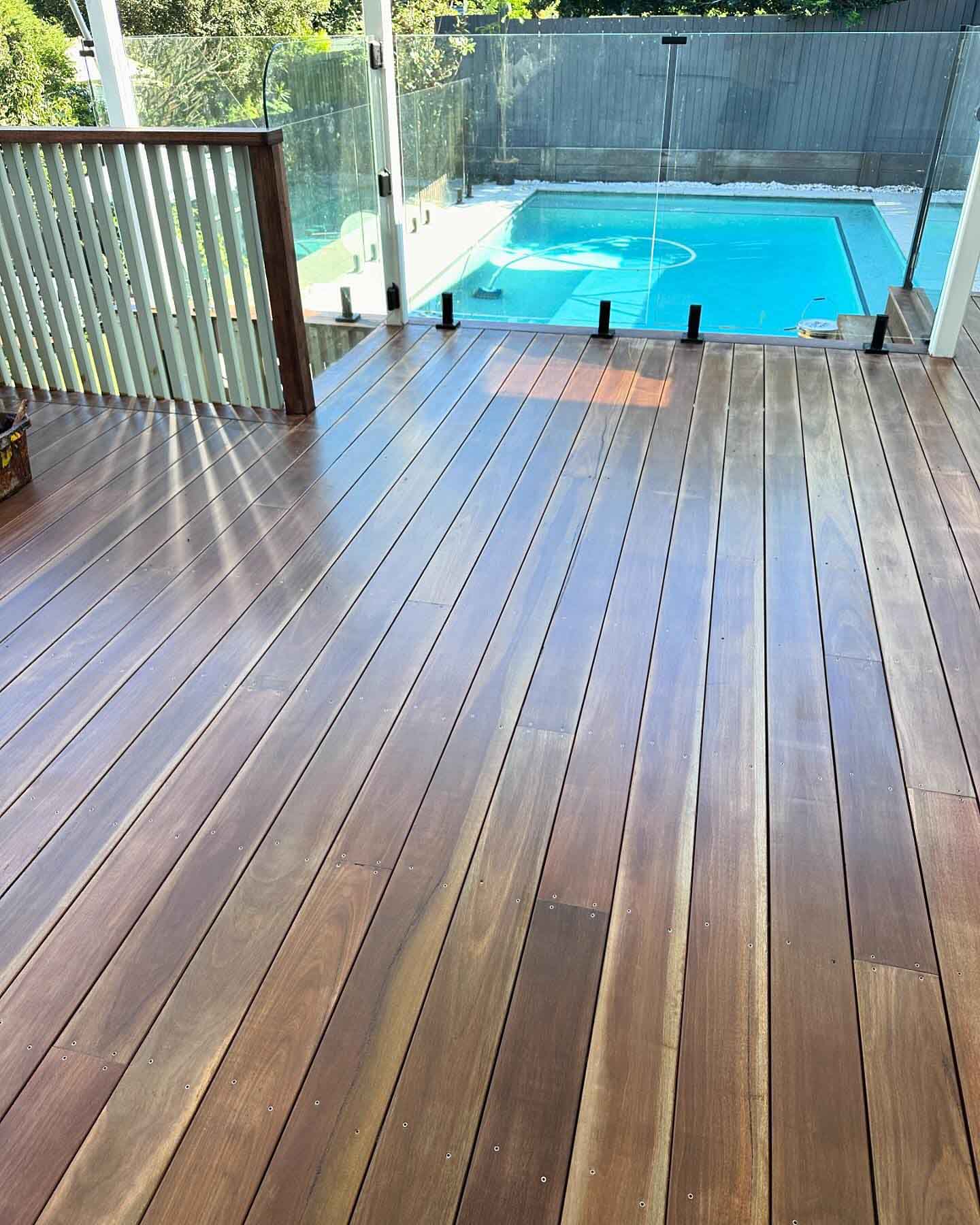 Oiled timber deck stretching towards a glass-fenced pool