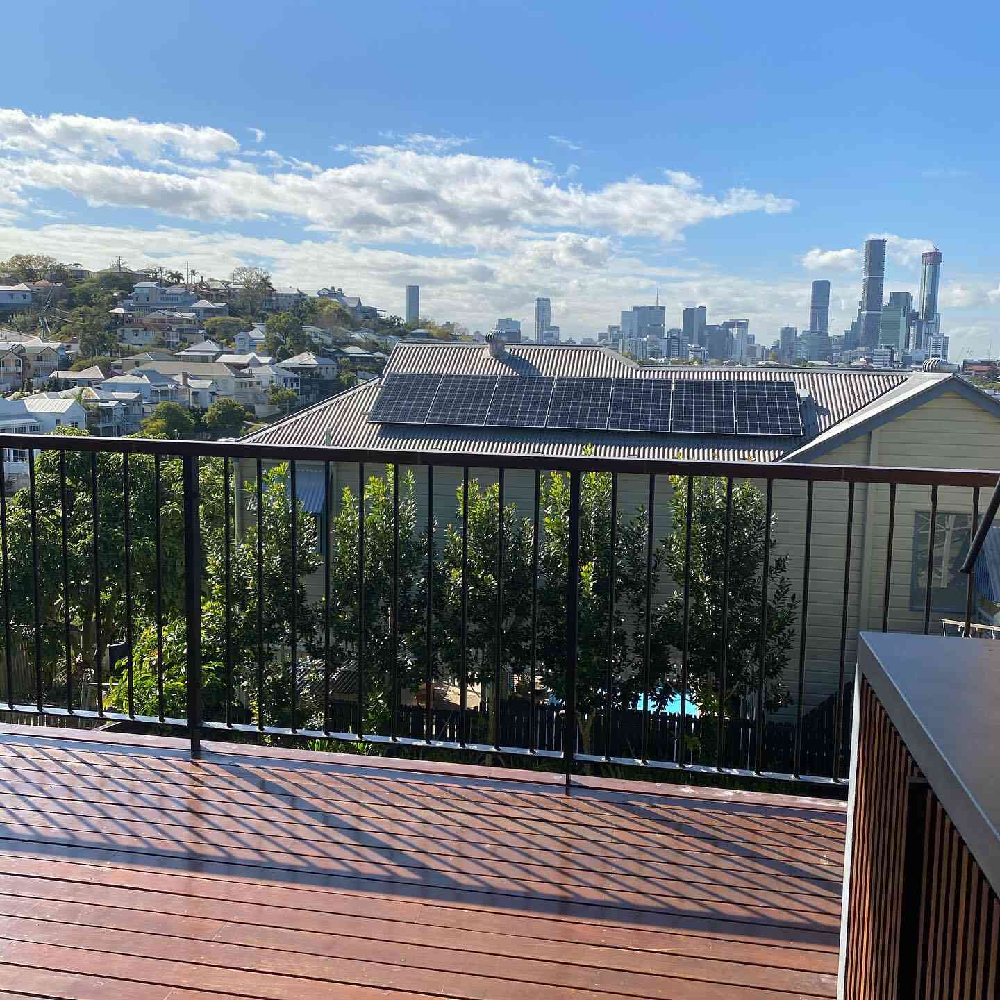Oiled timber deck with black balustrade overlooking a city skyline