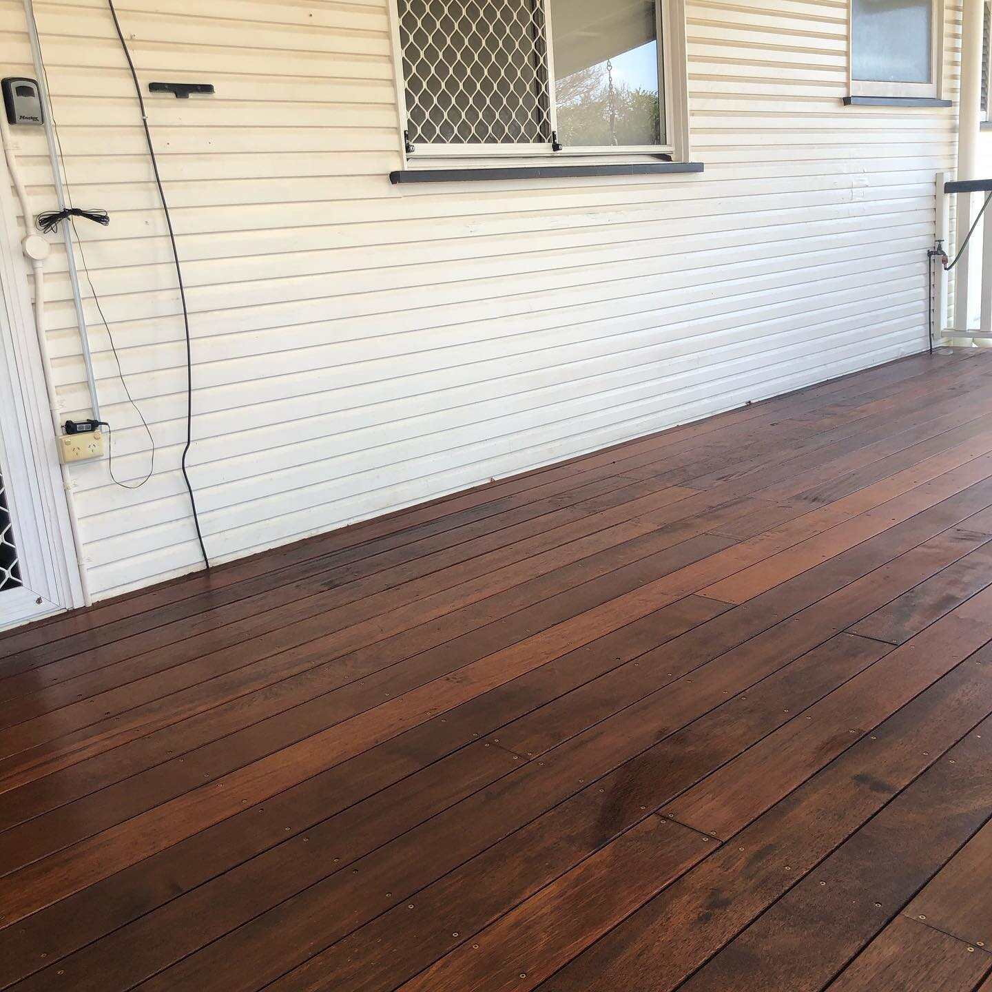 Dark oiled timber deck along a white weatherboard wall