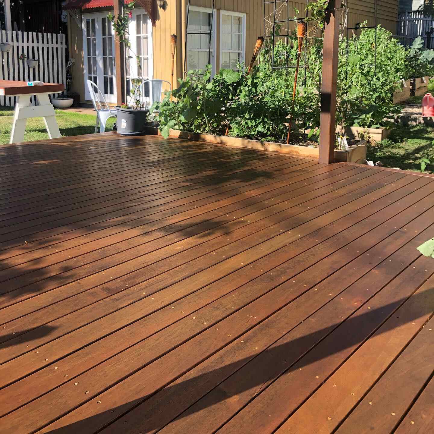 Oiled timber deck beside a vegetable garden and cubby house