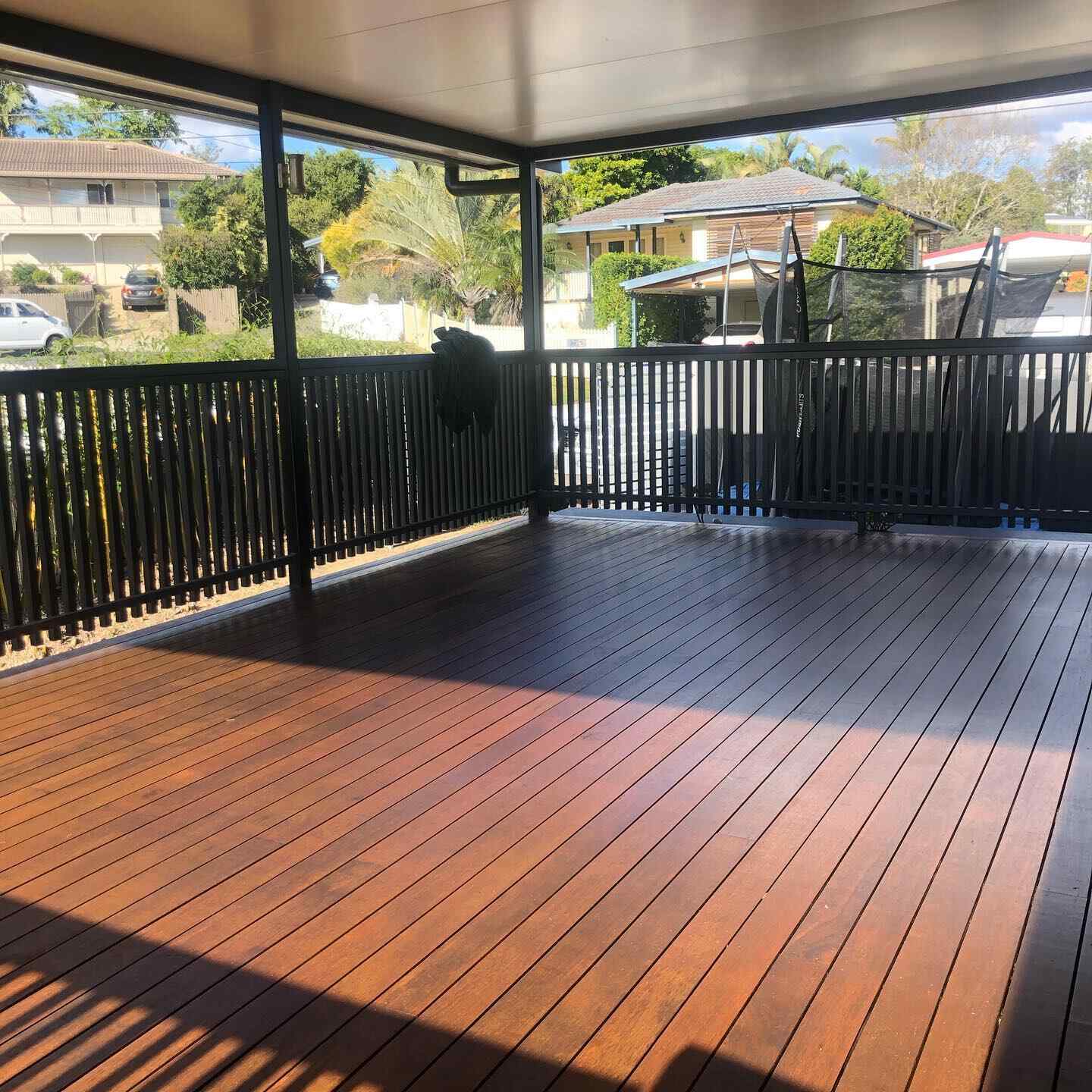 Oiled timber deck with dark timber balustrade under a patio roof