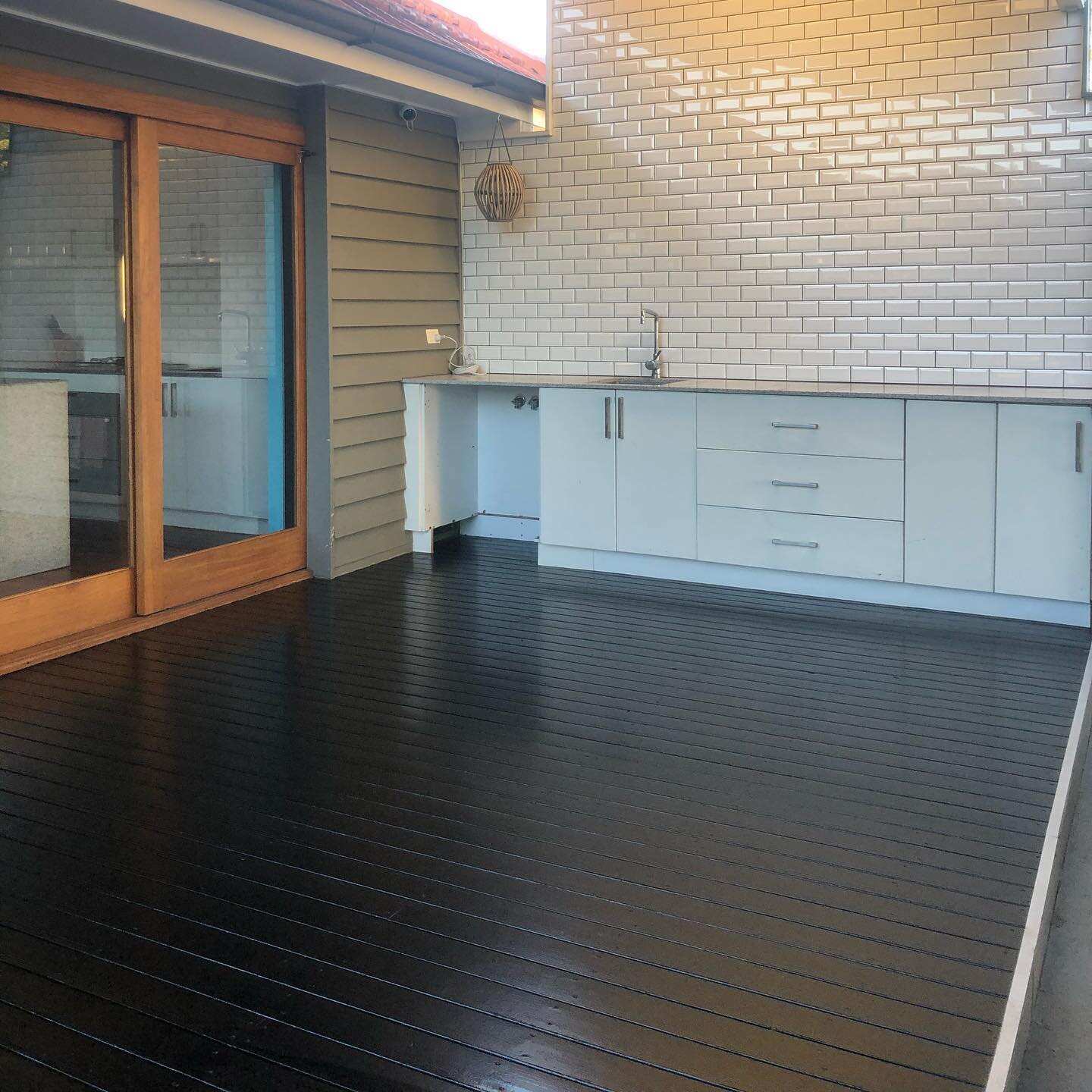 Black-stained deck beside an outdoor kitchen and timber sliding door