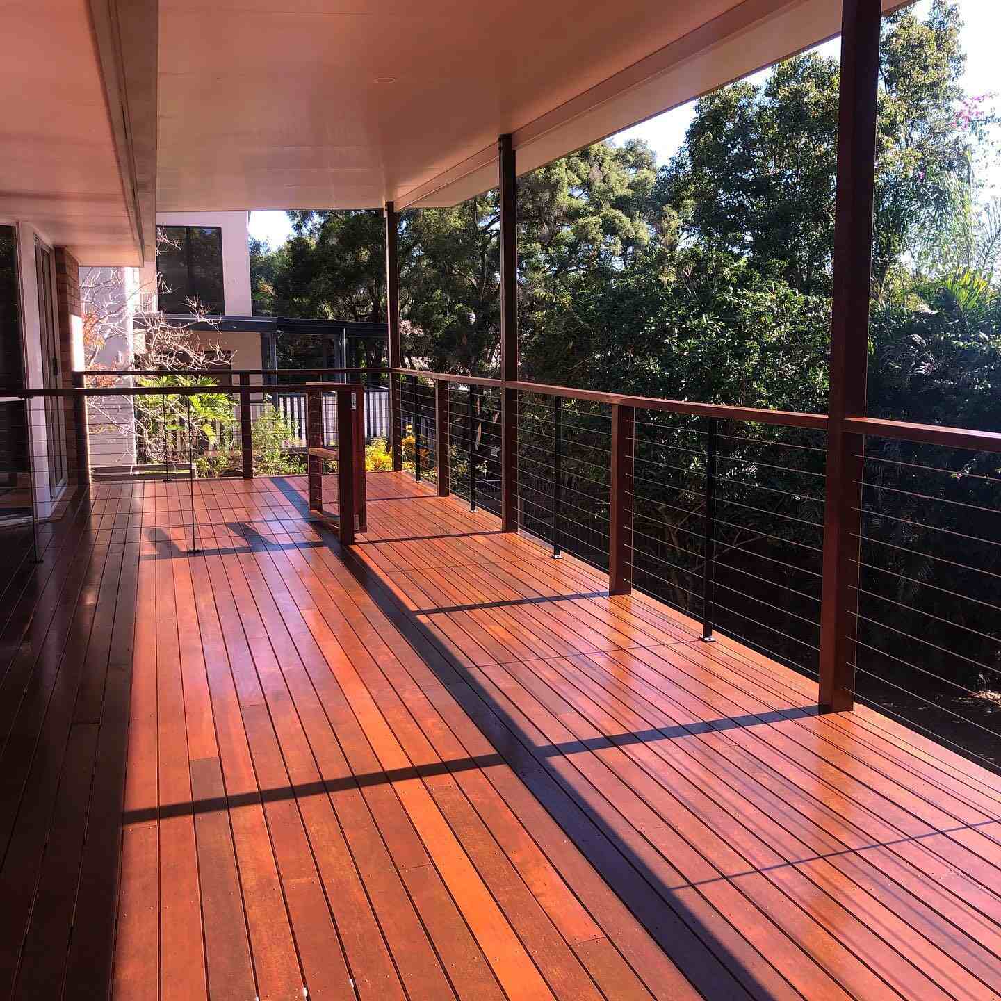 Oiled timber deck with red-toned timber and wire balustrade under a roof