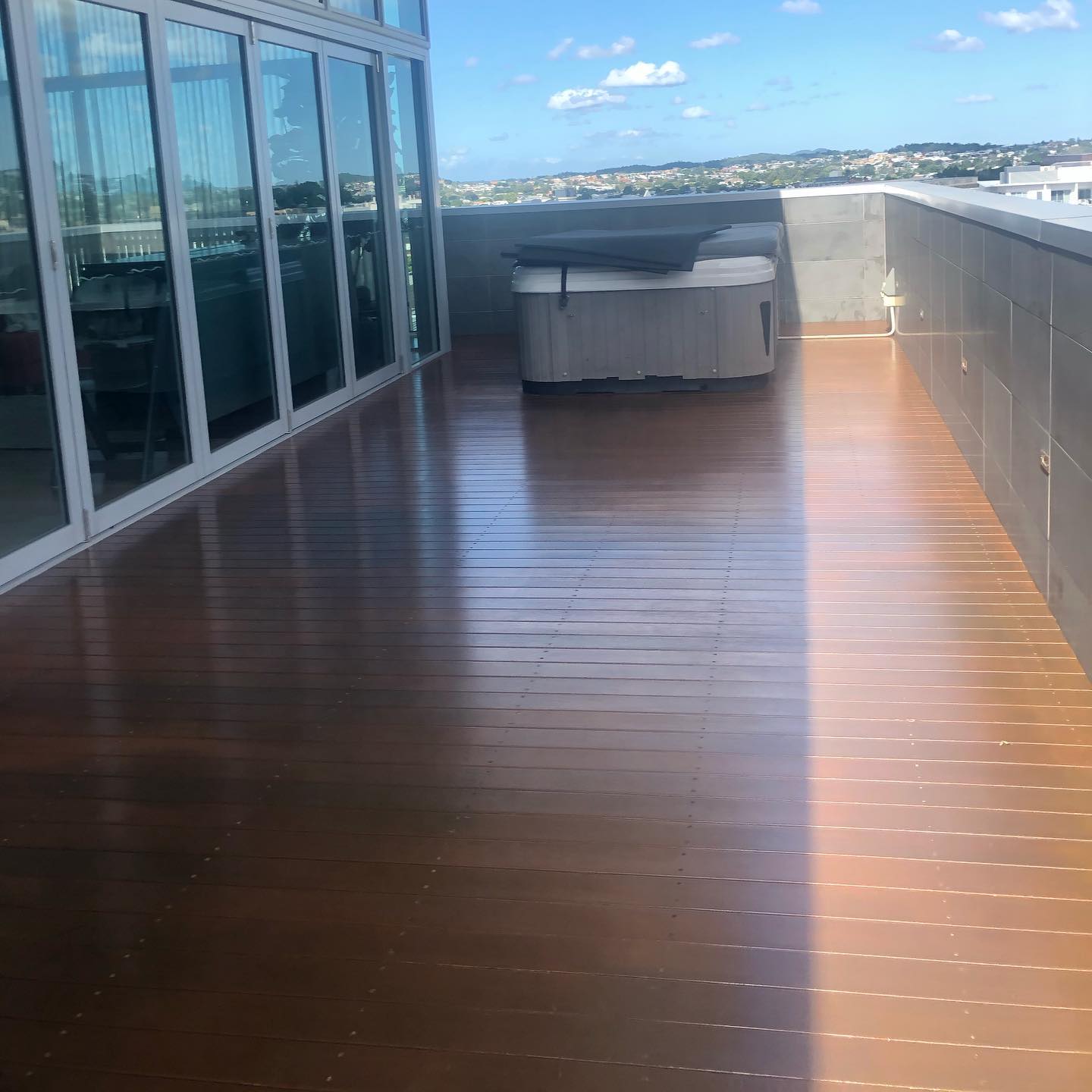 Glossy oiled timber rooftop deck with a spa and city views