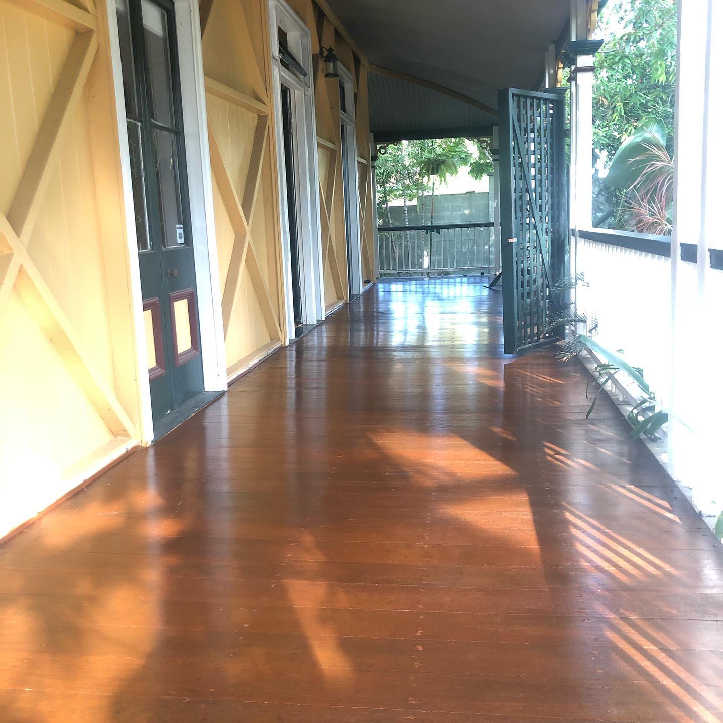 Long glossy timber verandah beside cream cross-braced walls and French doors
