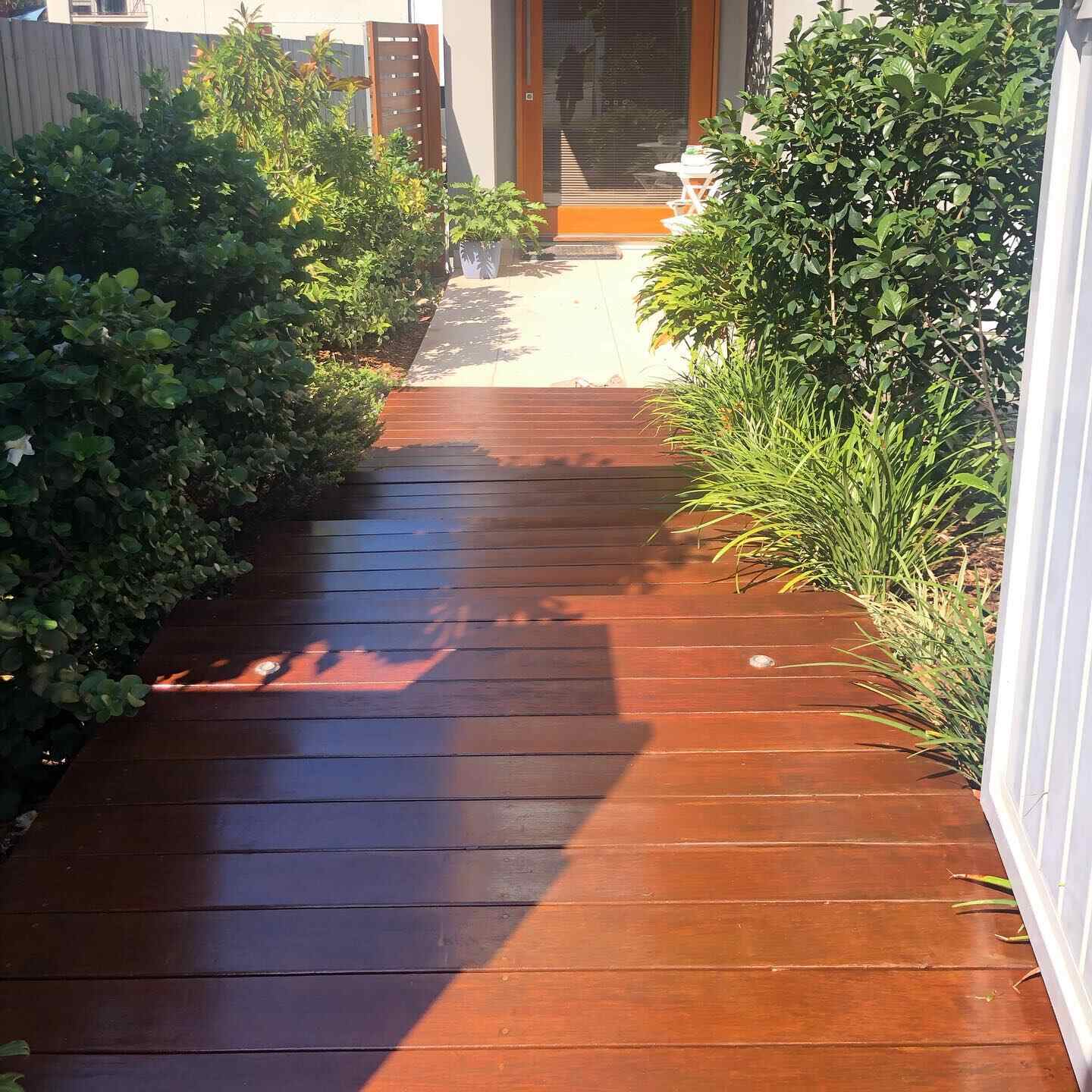 Glossy oiled timber path through a garden to a front door