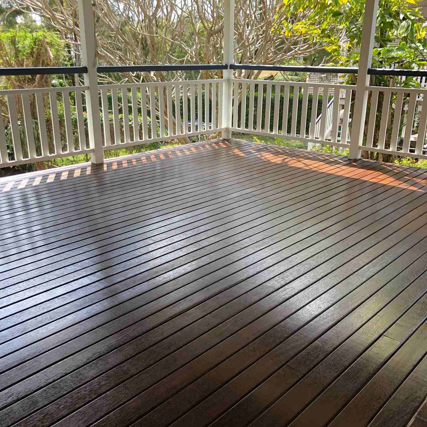 Glossy dark oiled timber verandah corner with white balustrade