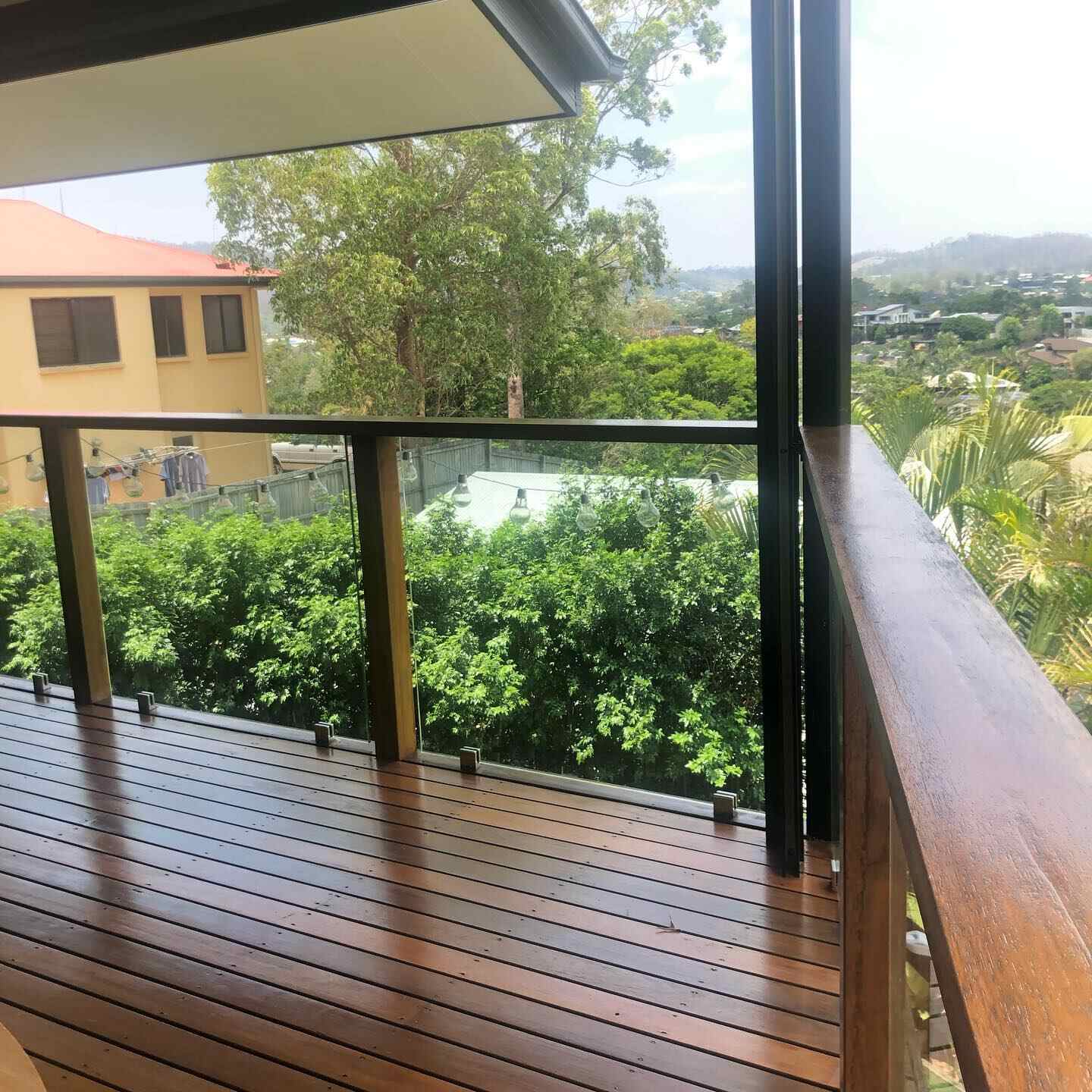 Oiled timber deck with timber-capped glass balustrade overlooking hills