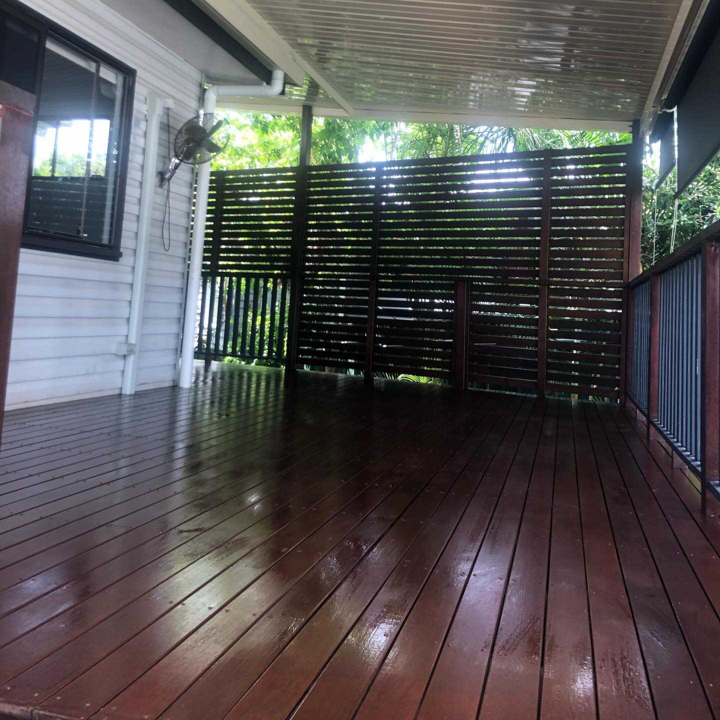 Glossy dark oiled timber deck with a timber slat privacy screen