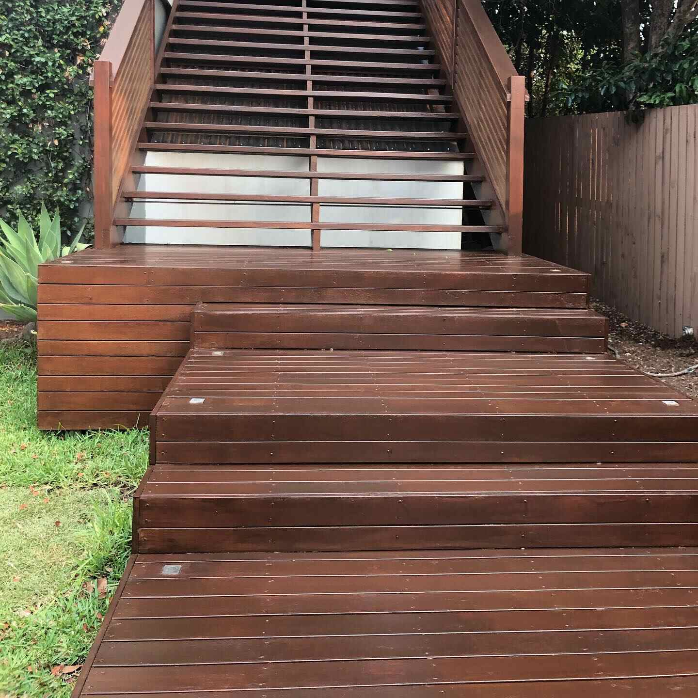 Oiled timber stairs and landing with timber balustrade beside a lawn