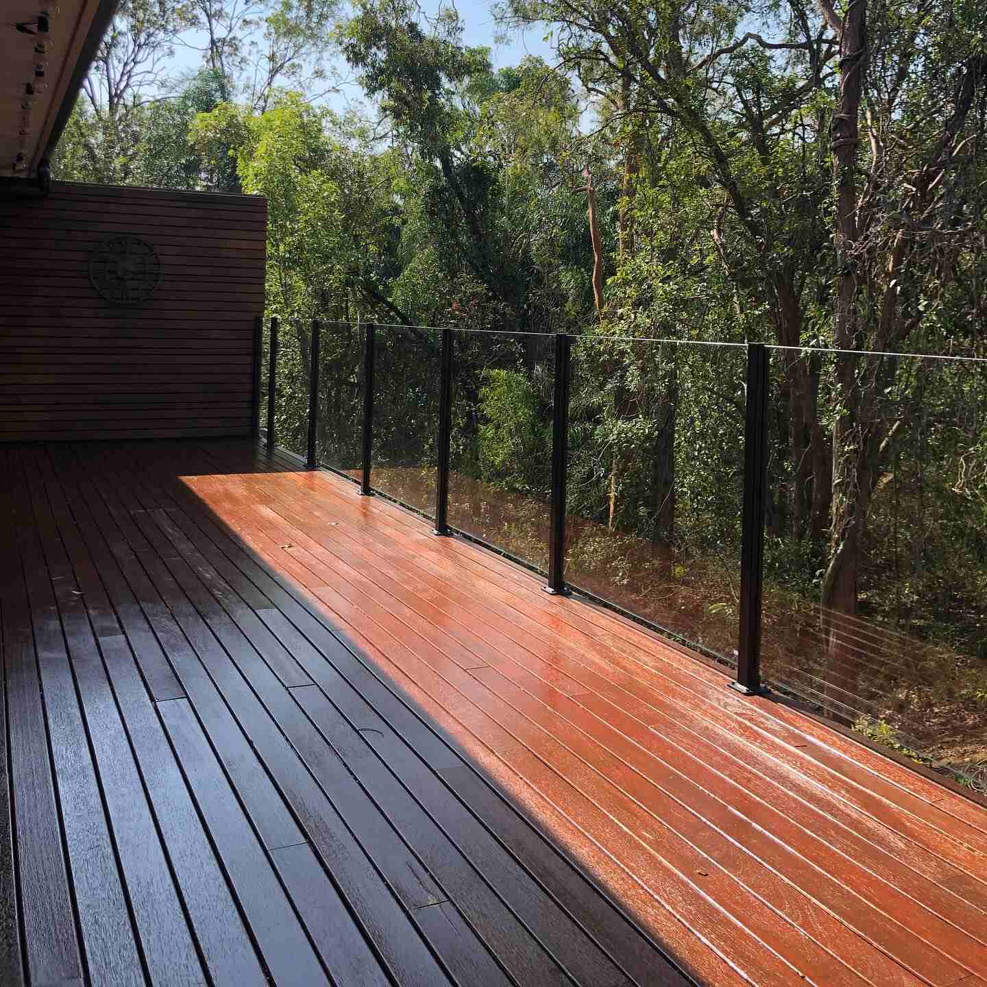 Two-tone timber deck, half oiled and half dark, with wire balustrade in bushland