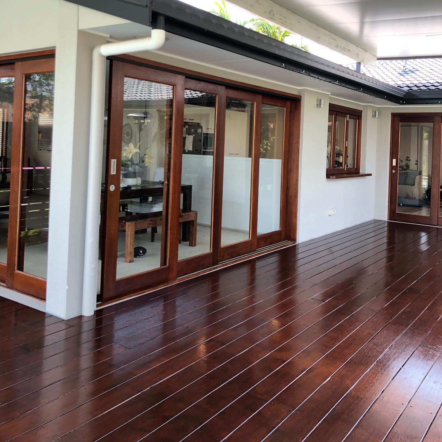 Glossy oiled timber deck along timber-framed sliding doors