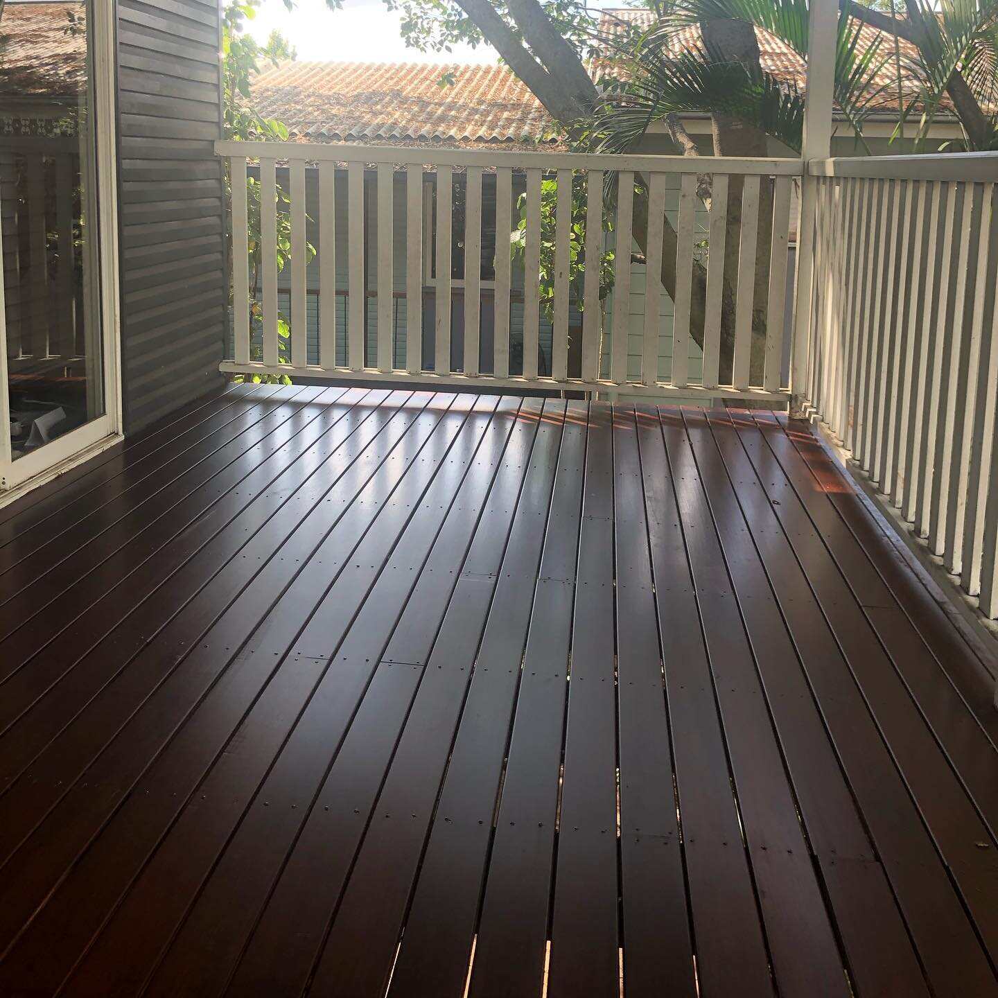 Dark oiled timber verandah with white timber balustrade, corner view