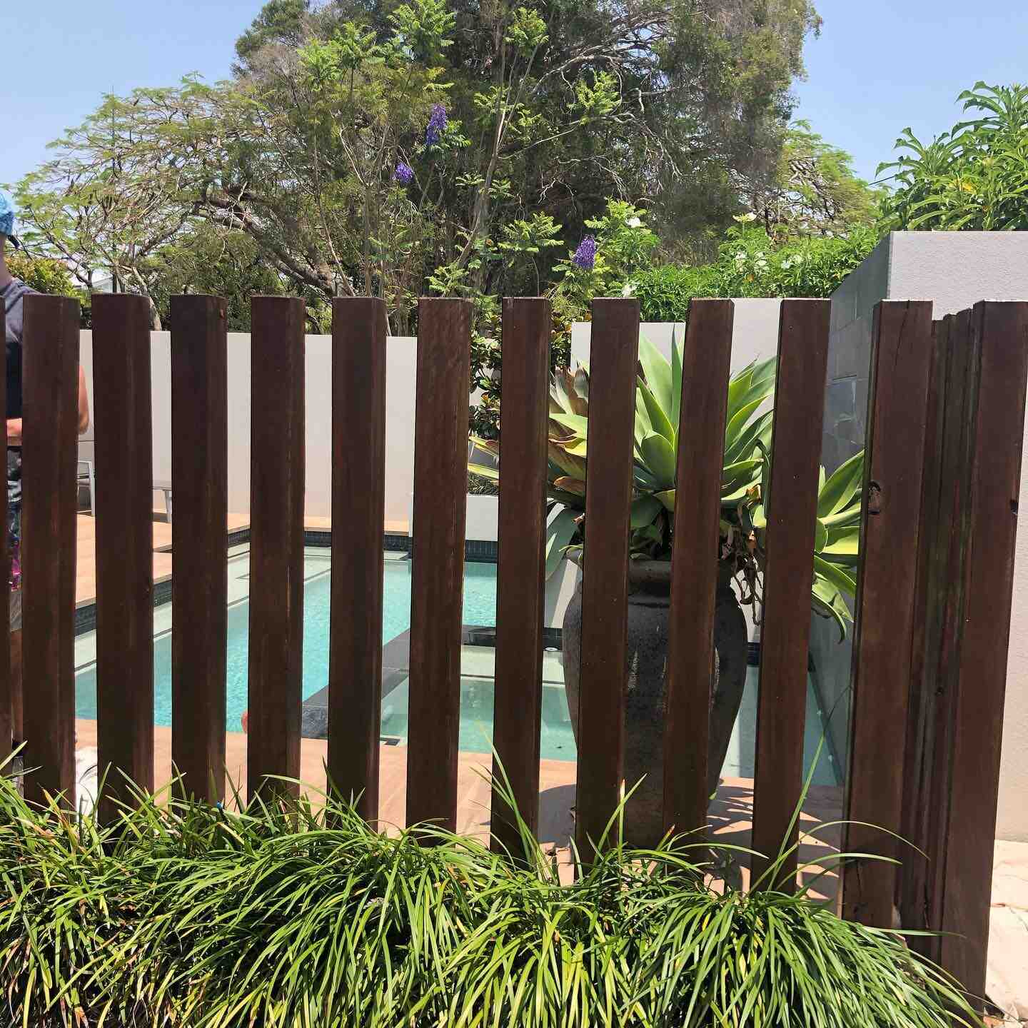 Vertical timber batten pool fence with a garden bed in front