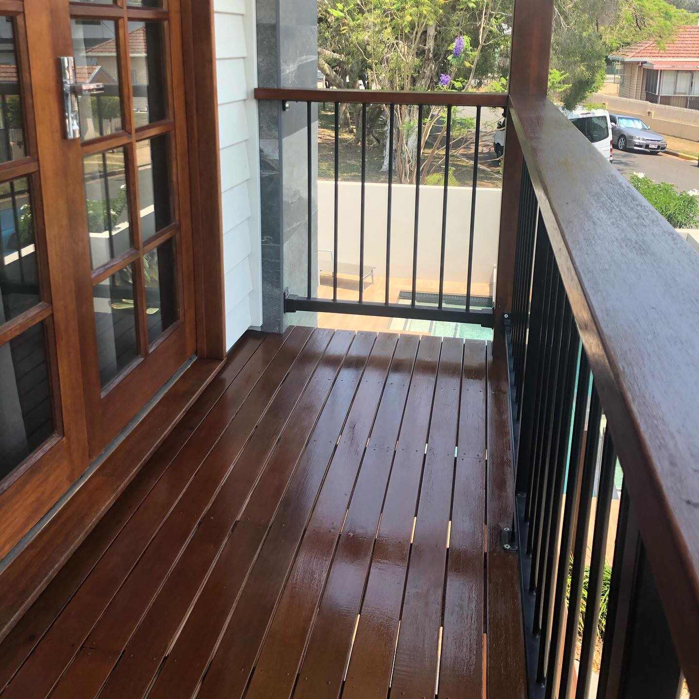 Glossy oiled timber balcony with timber-capped black balustrade