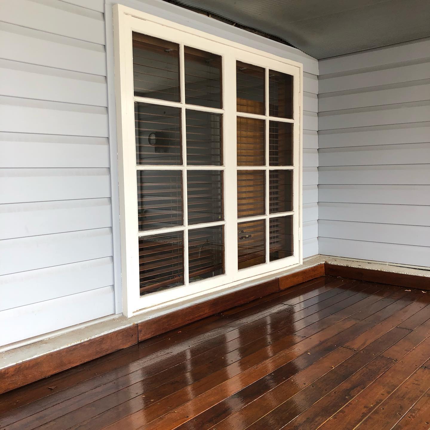 Glossy oiled timber floor in front of a white-framed window and weatherboards