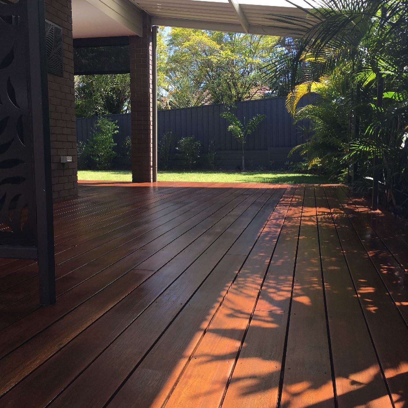 Oiled timber deck beside a decorative screen leading to a lawn