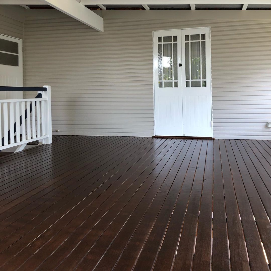 Dark oiled timber verandah outside white French doors