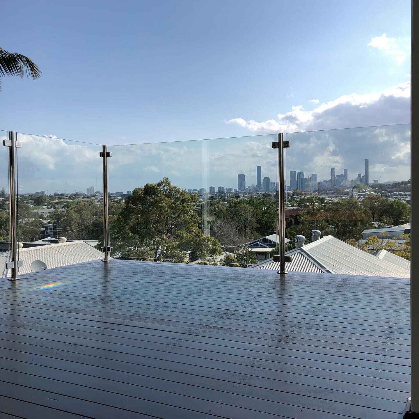 Dark-coated deck with glass balustrade overlooking a city skyline