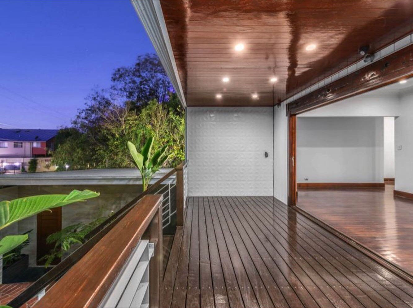 Oiled timber balcony deck under a timber-lined ceiling at dusk