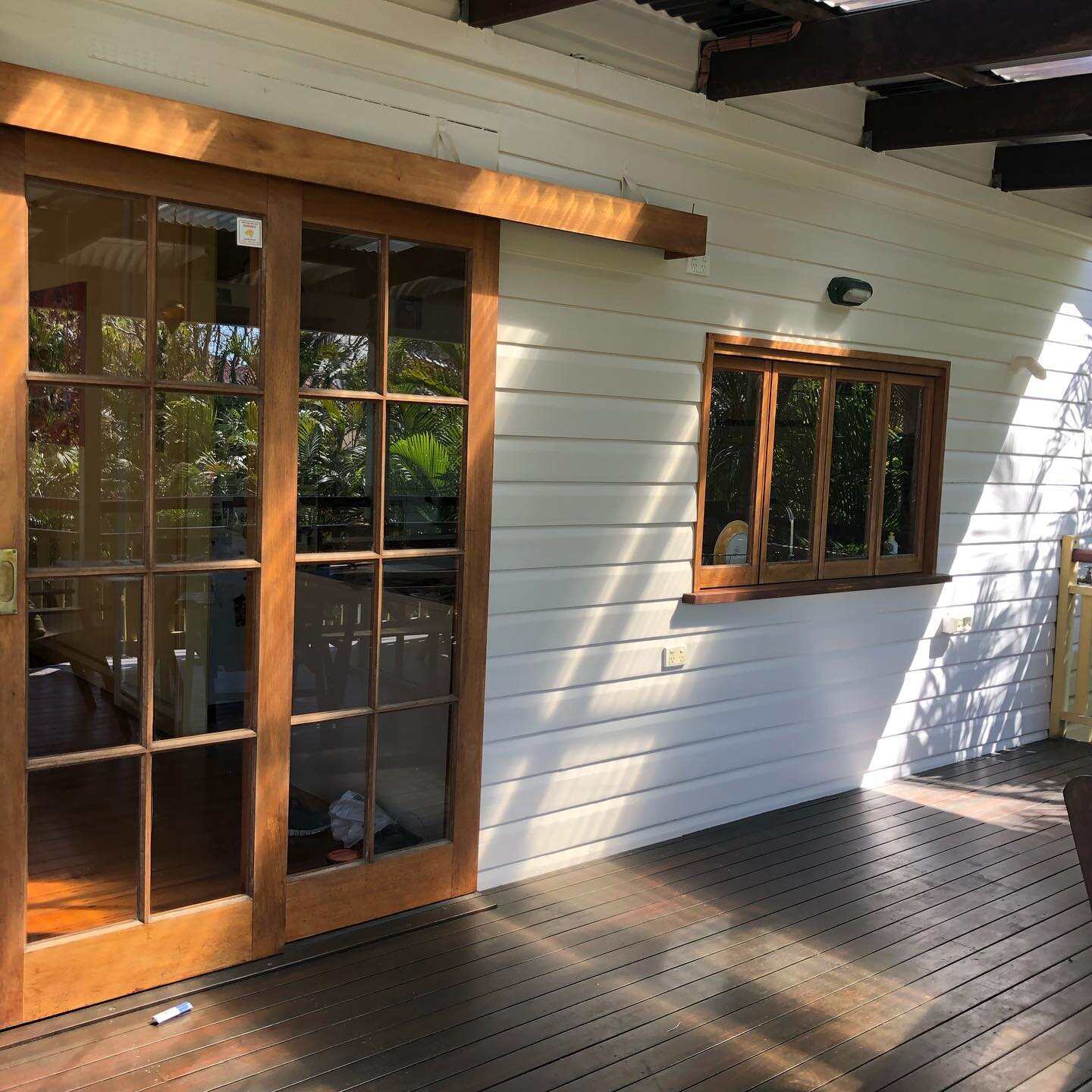 Dark oiled timber verandah outside timber French doors on a white house