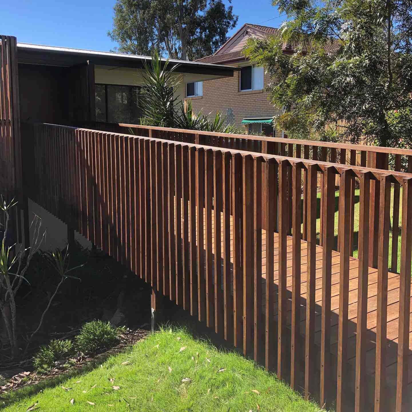 Oiled timber picket balustrade along a deck beside a lawn