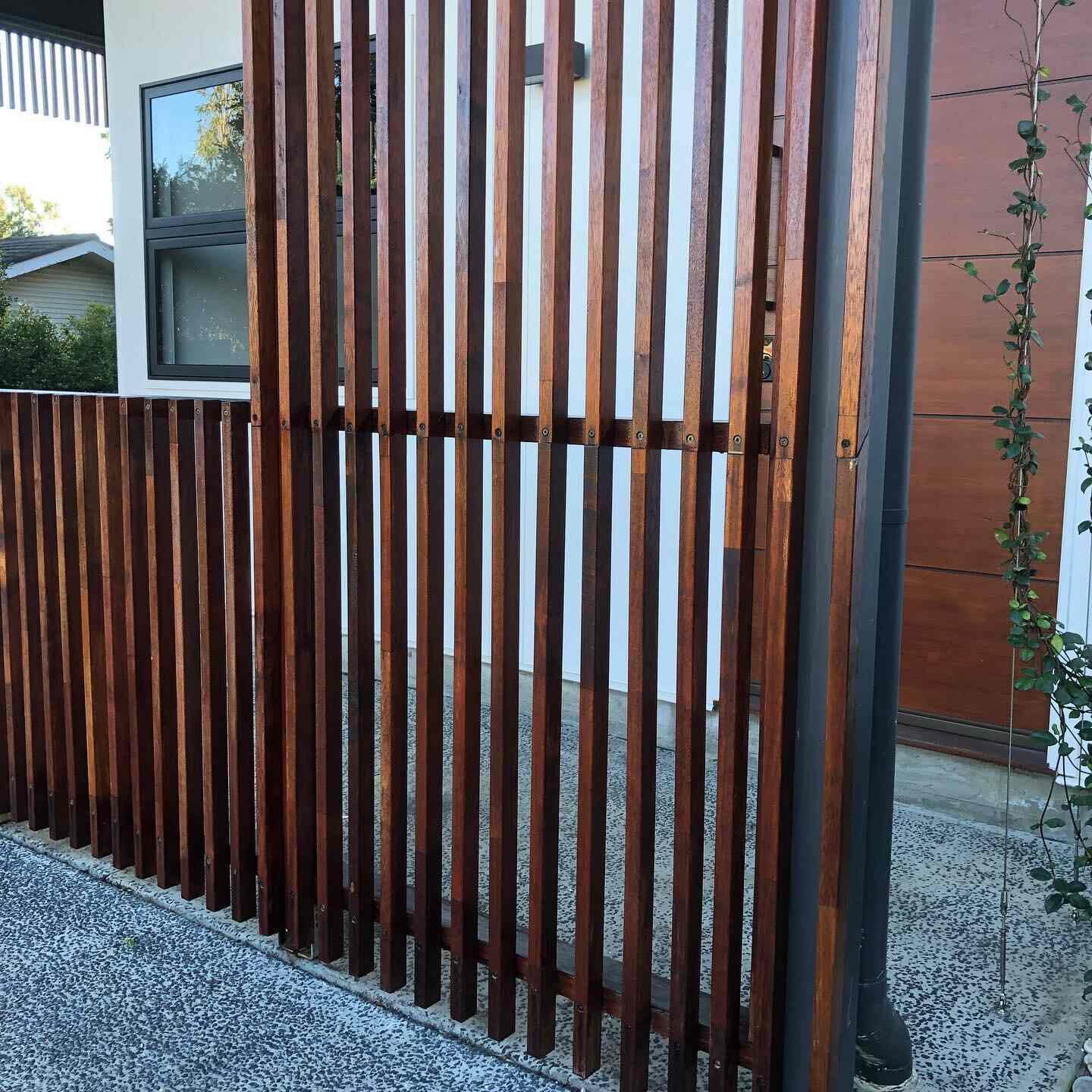 Oiled vertical timber batten screen and fence beside a driveway
