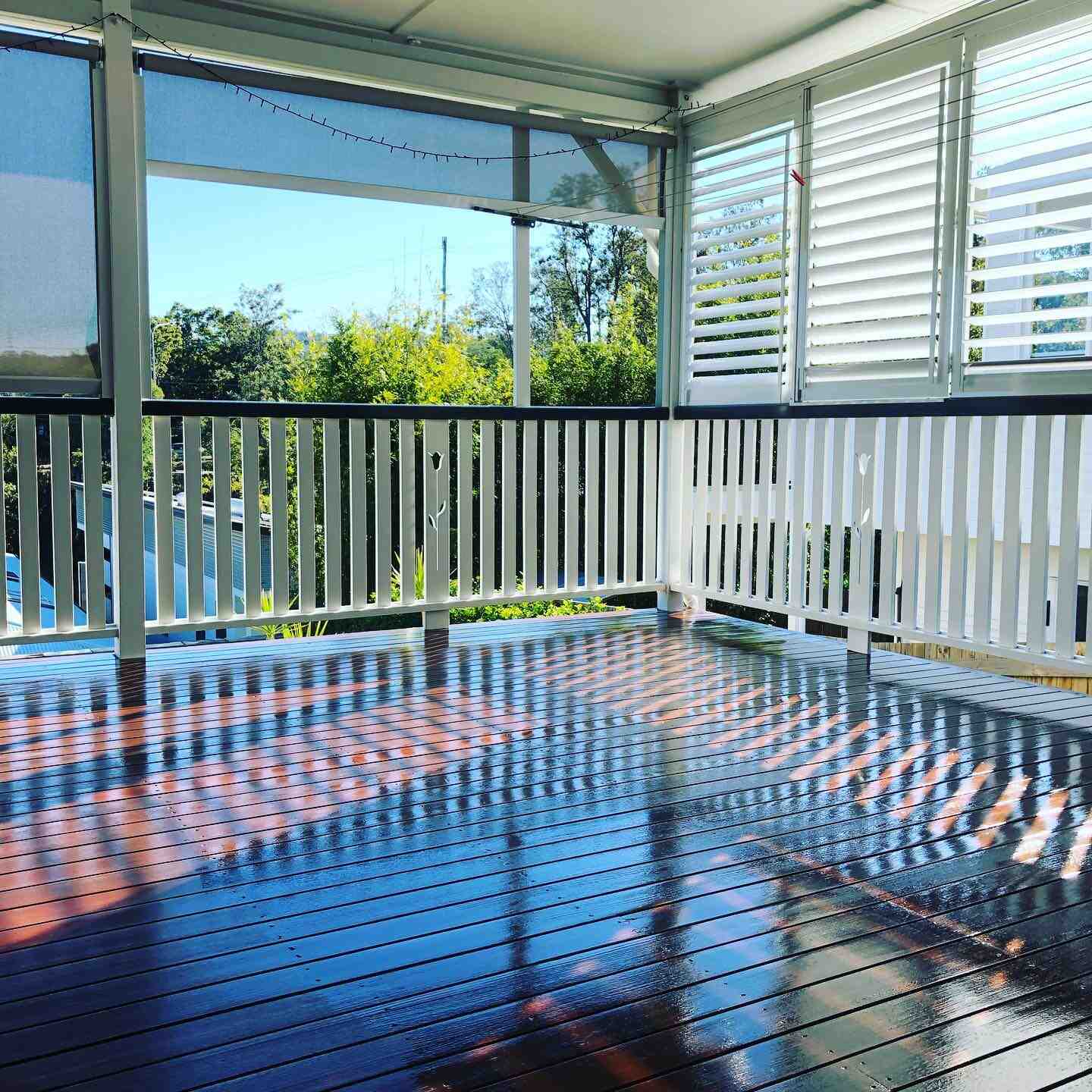 Glossy oiled timber deck with white balustrade and white plantation shutters