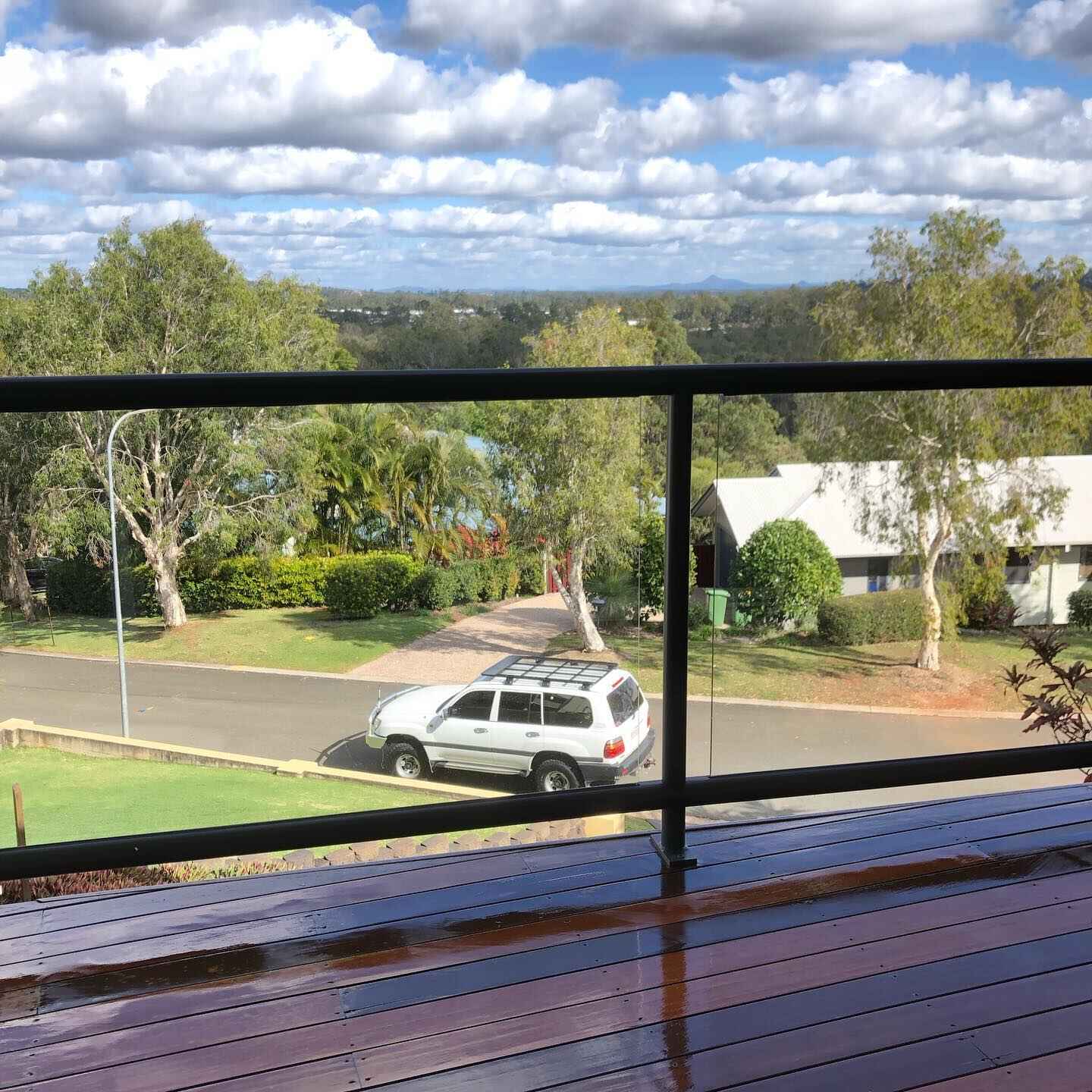 Wet oiled timber deck with black balustrade overlooking a street