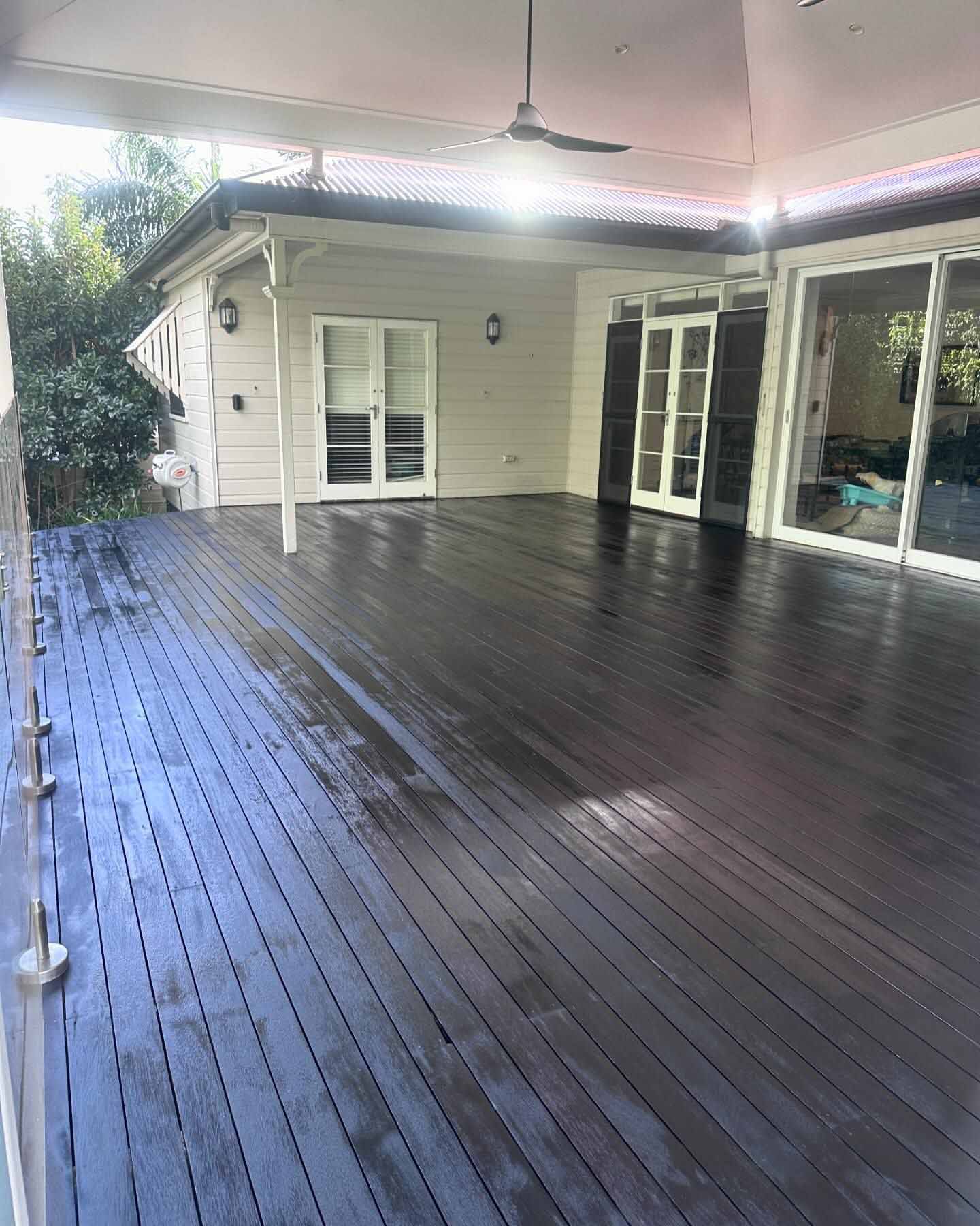 Wet charcoal-stained deck under a pavilion roof outside French doors