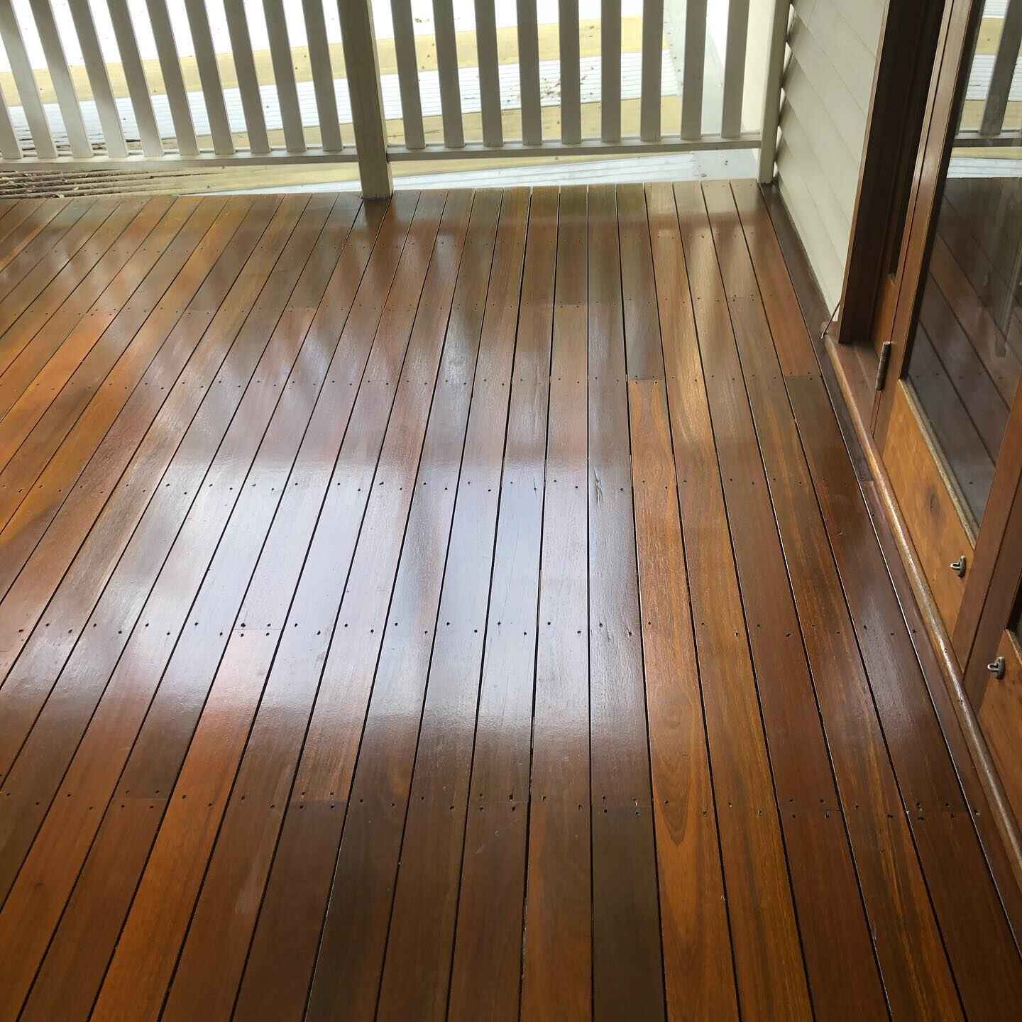 Glossy oiled timber deck under a white slatted pergola