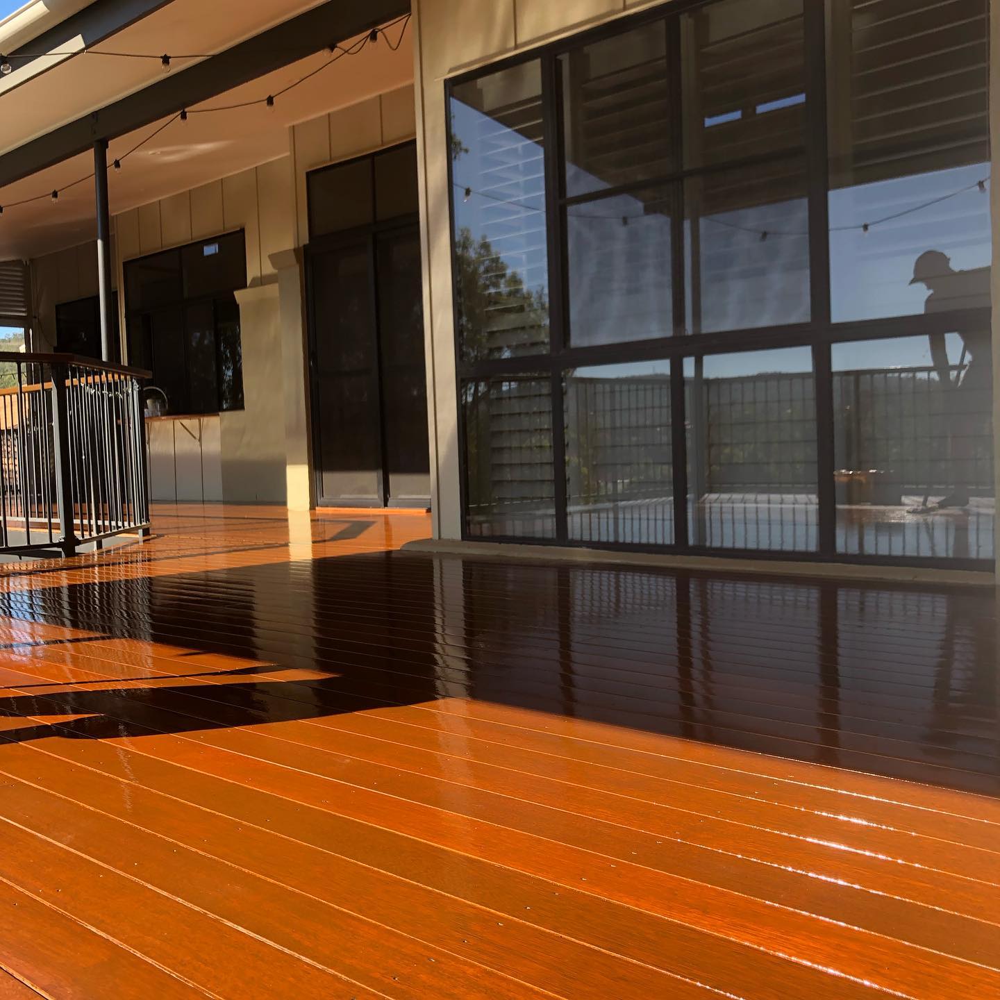 Freshly oiled orange-toned timber deck along black-framed windows