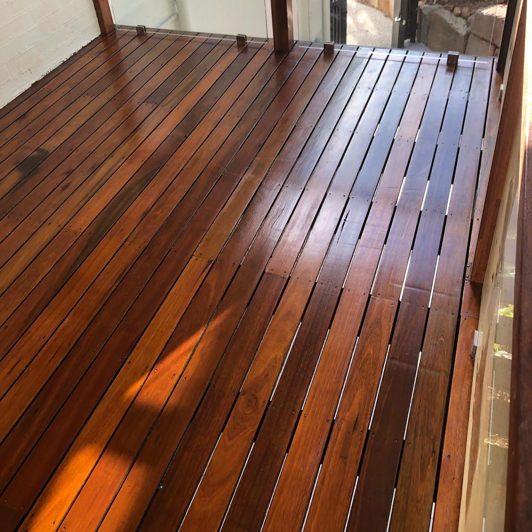 Glossy oiled timber deck seen from above, beside a glass door