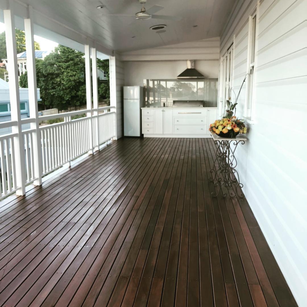 Dark oiled timber verandah with white balustrade and an outdoor kitchen
