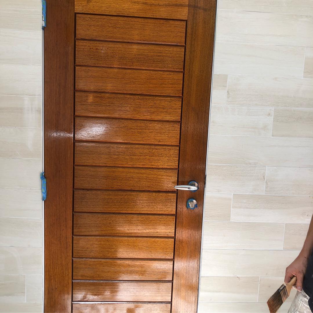 Freshly oiled timber door, with a painter's brush in view