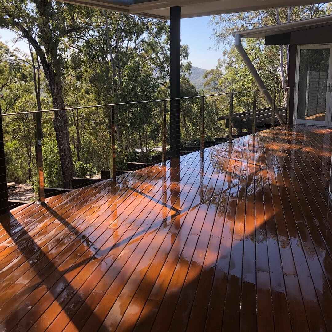 Glossy wet oiled timber deck with wire balustrade overlooking bushland