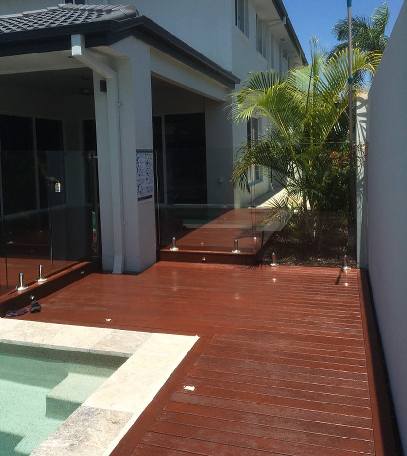 Oiled timber deck around a plunge pool beside a white rendered house