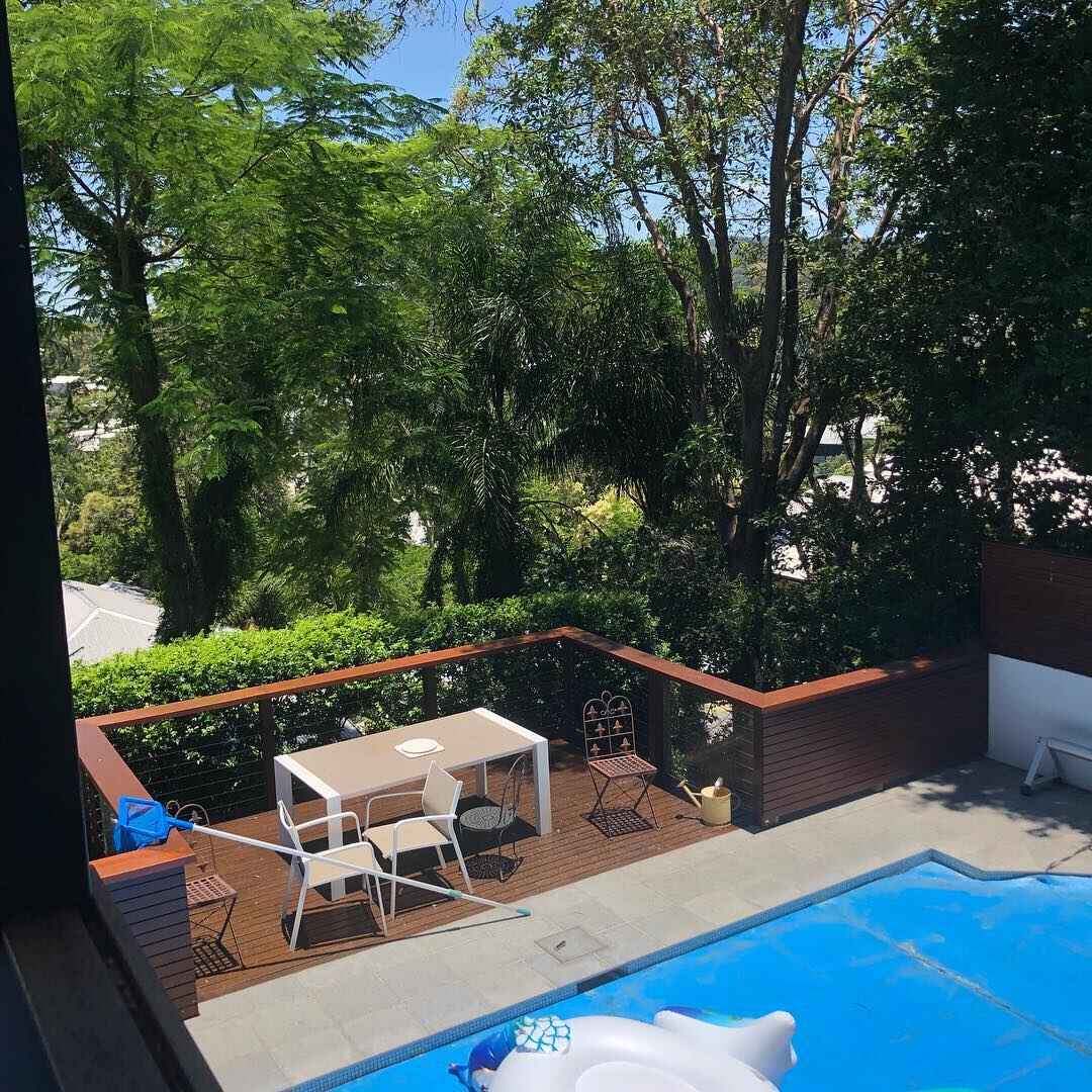 Timber deck with outdoor dining setting above a pool, seen from above