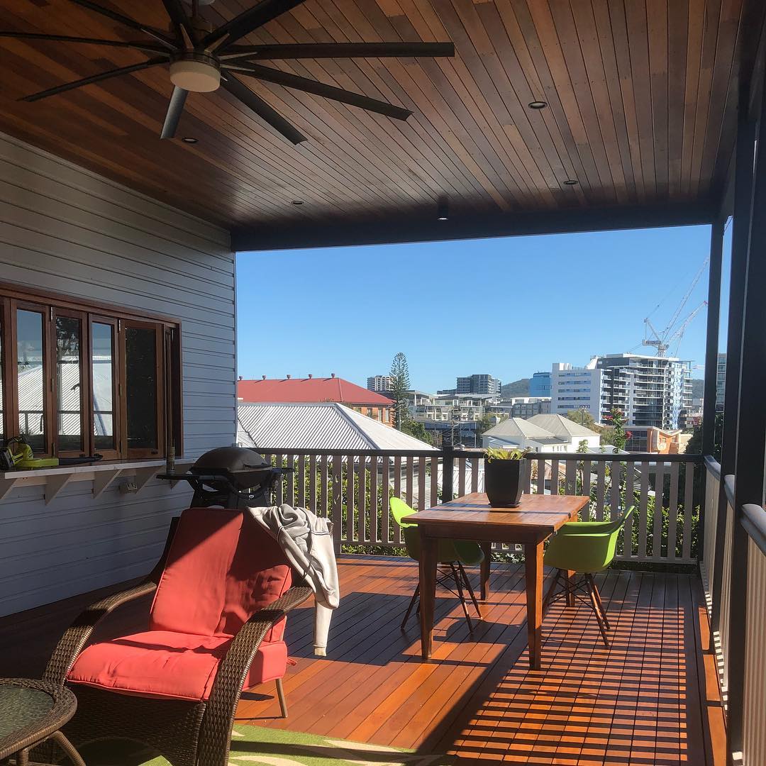 Oiled timber deck under a timber-lined ceiling with outdoor furniture and city view