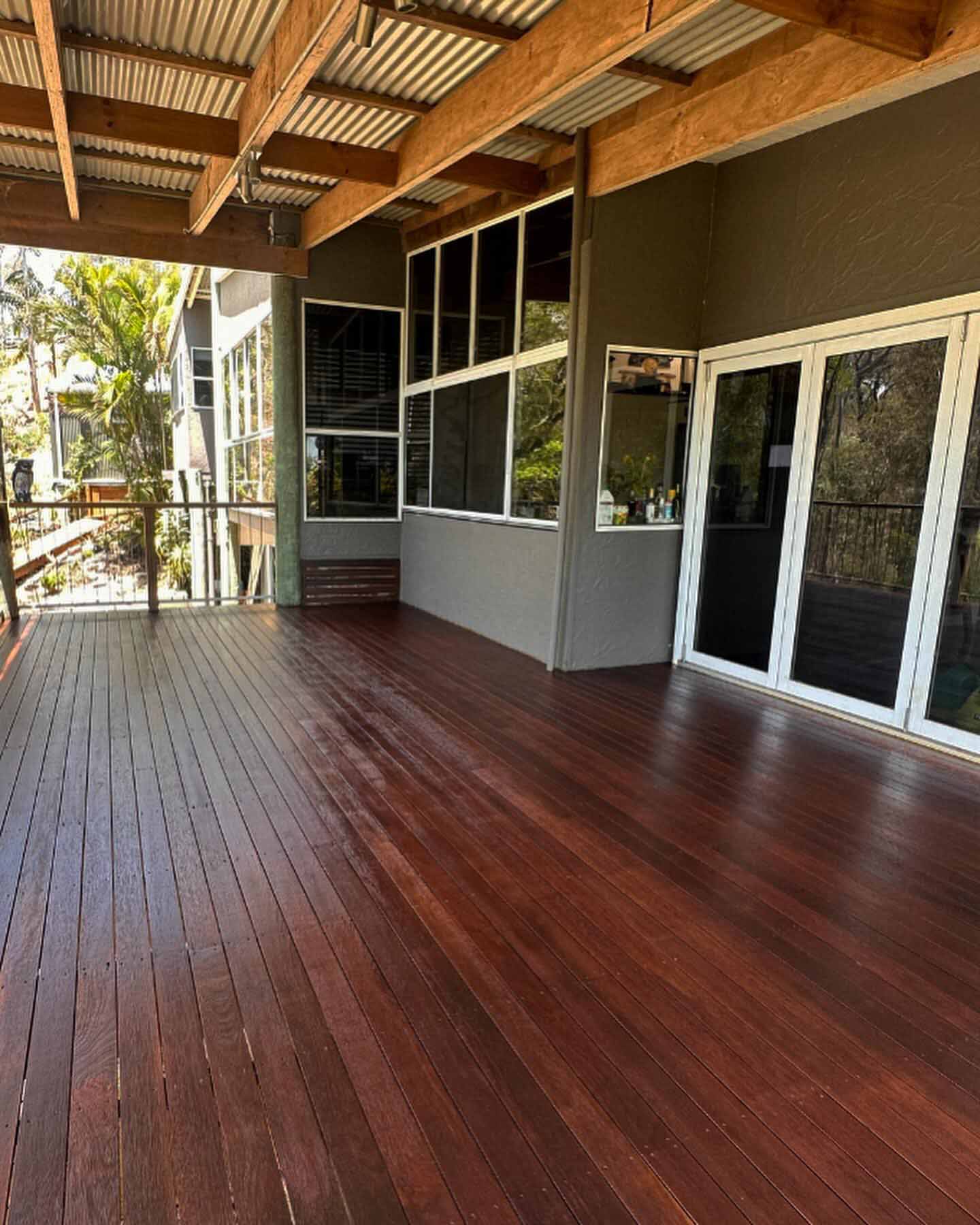 Oiled timber verandah under an exposed-rafter roof beside glass sliding doors