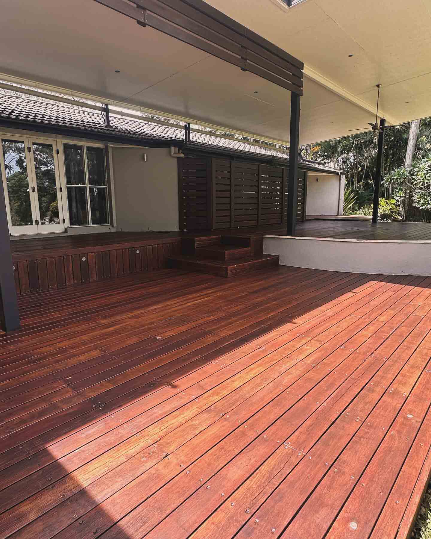 Oiled timber deck under a patio roof with timber slat screens and steps