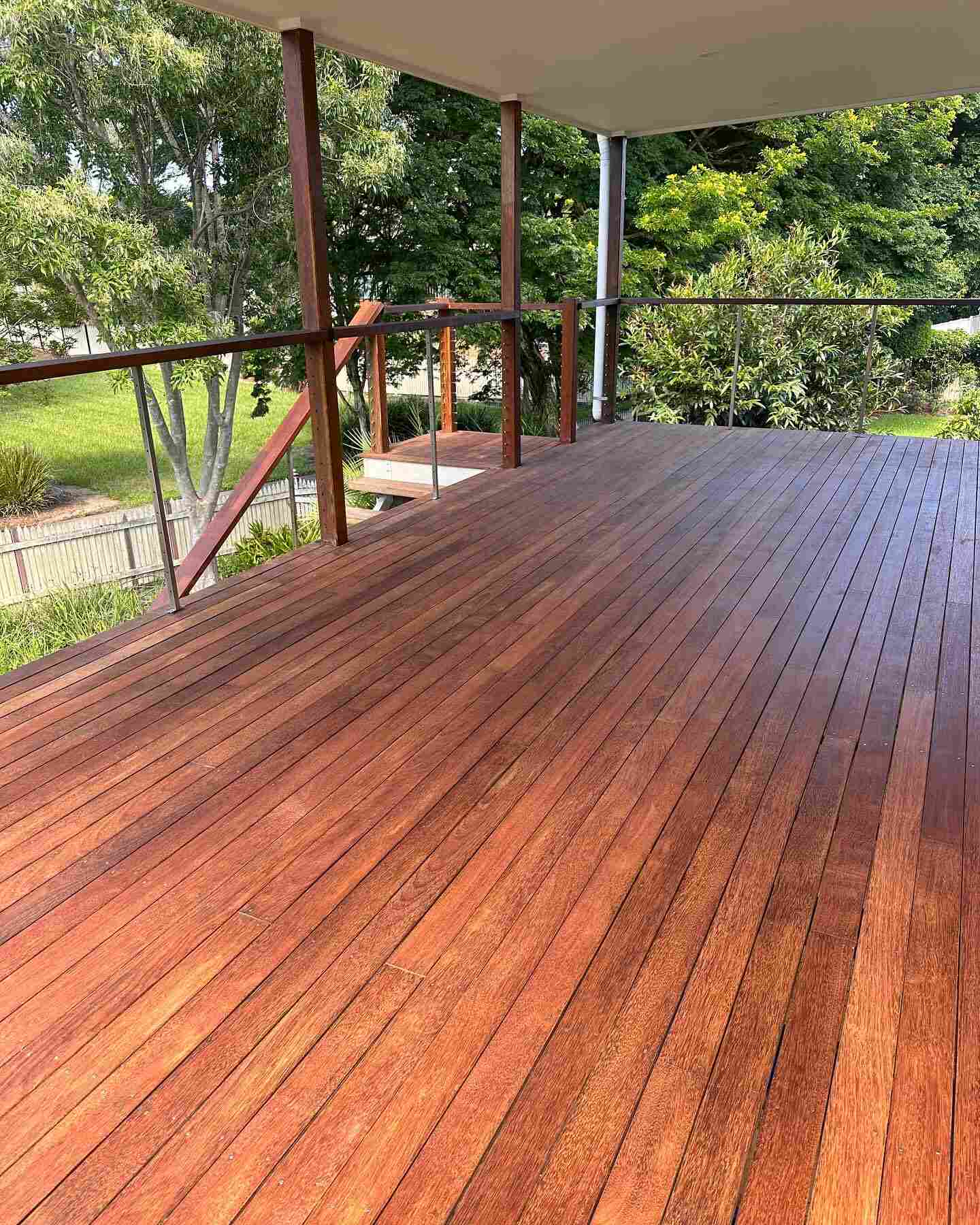 Long oiled timber deck with red-toned timber balustrade overlooking trees