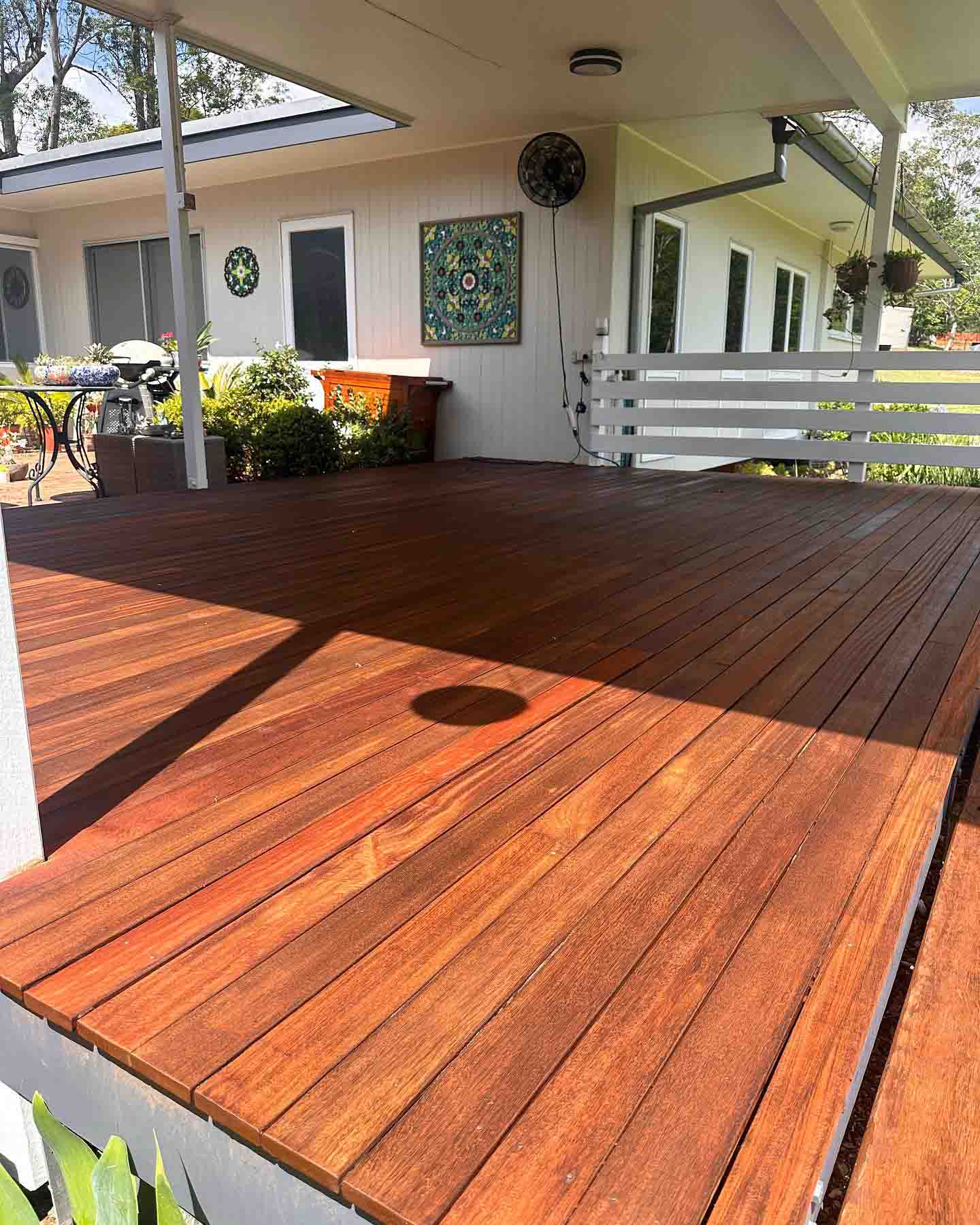 Oiled timber deck under a patio roof with a white slatted balustrade