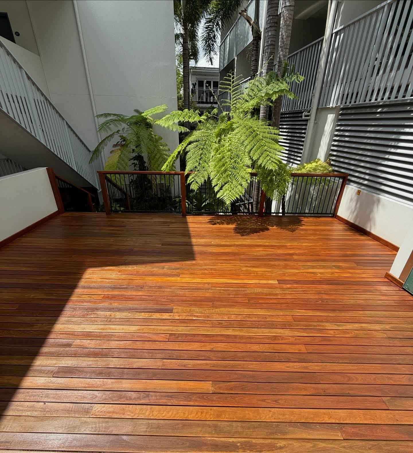 Same courtyard deck from the far end, with tree ferns and a timber-topped balustrade