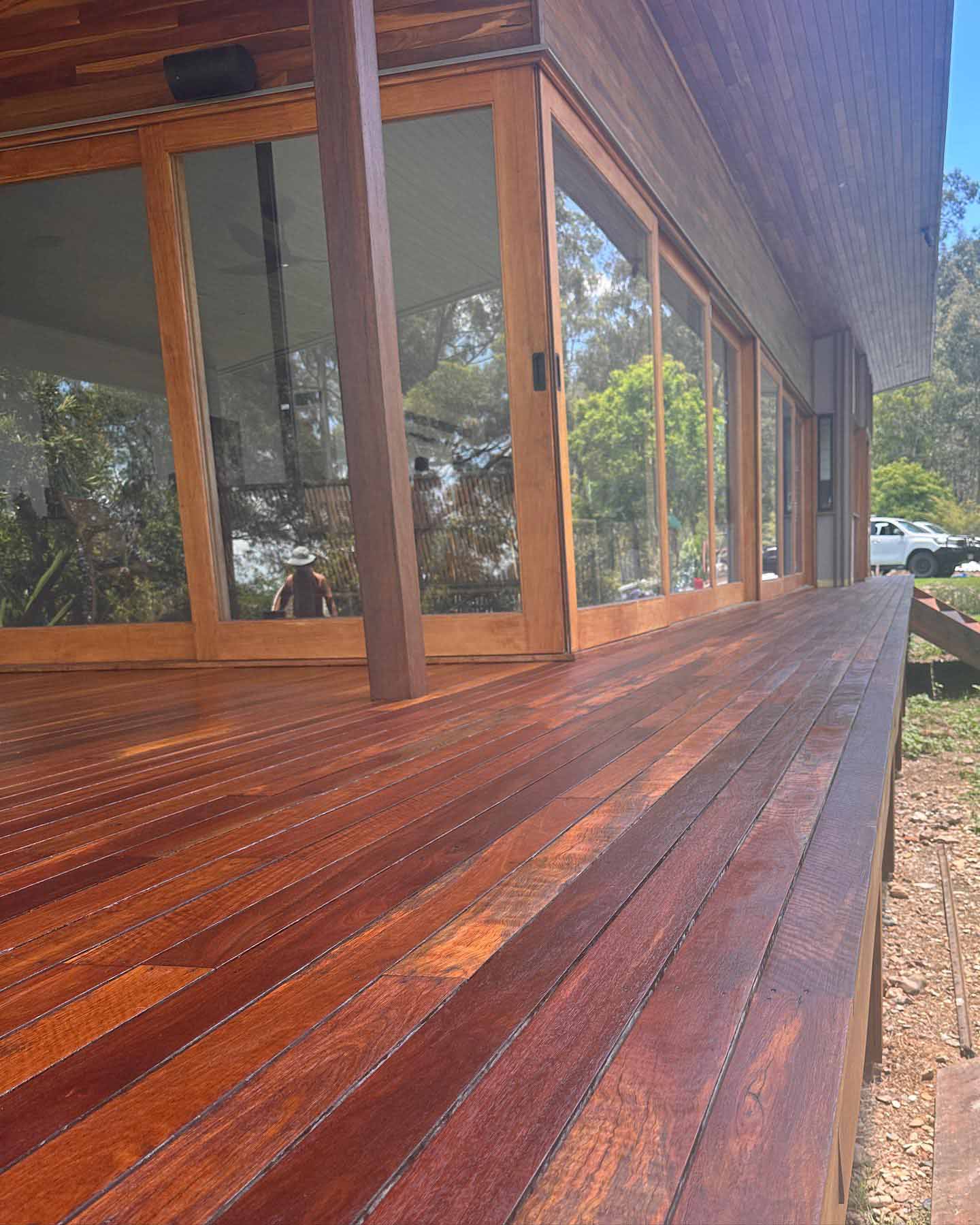 Oiled timber deck along floor-to-ceiling timber-framed windows