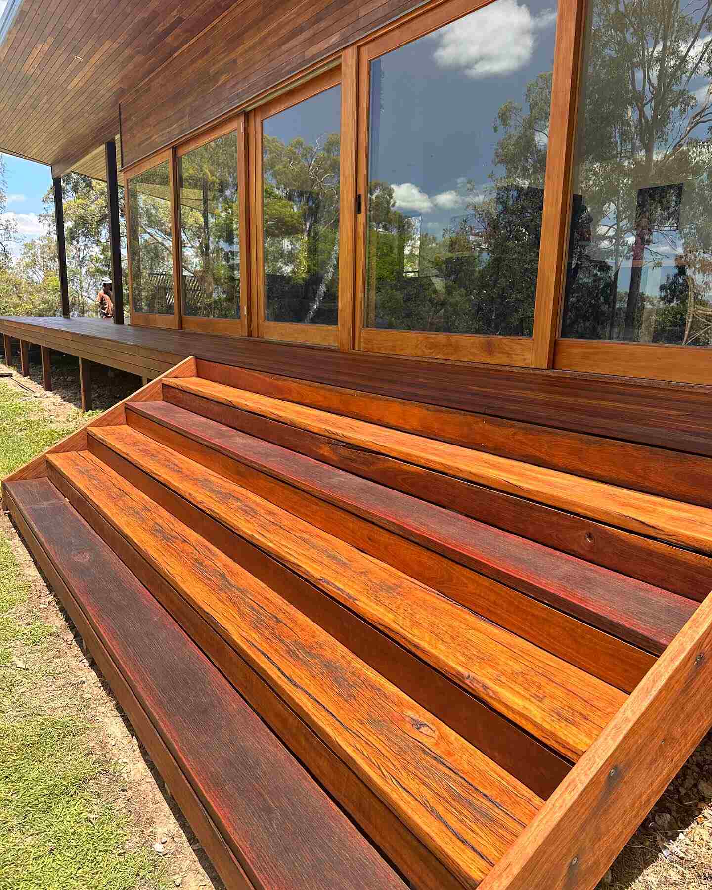 Wide oiled timber steps leading up to a timber-clad house
