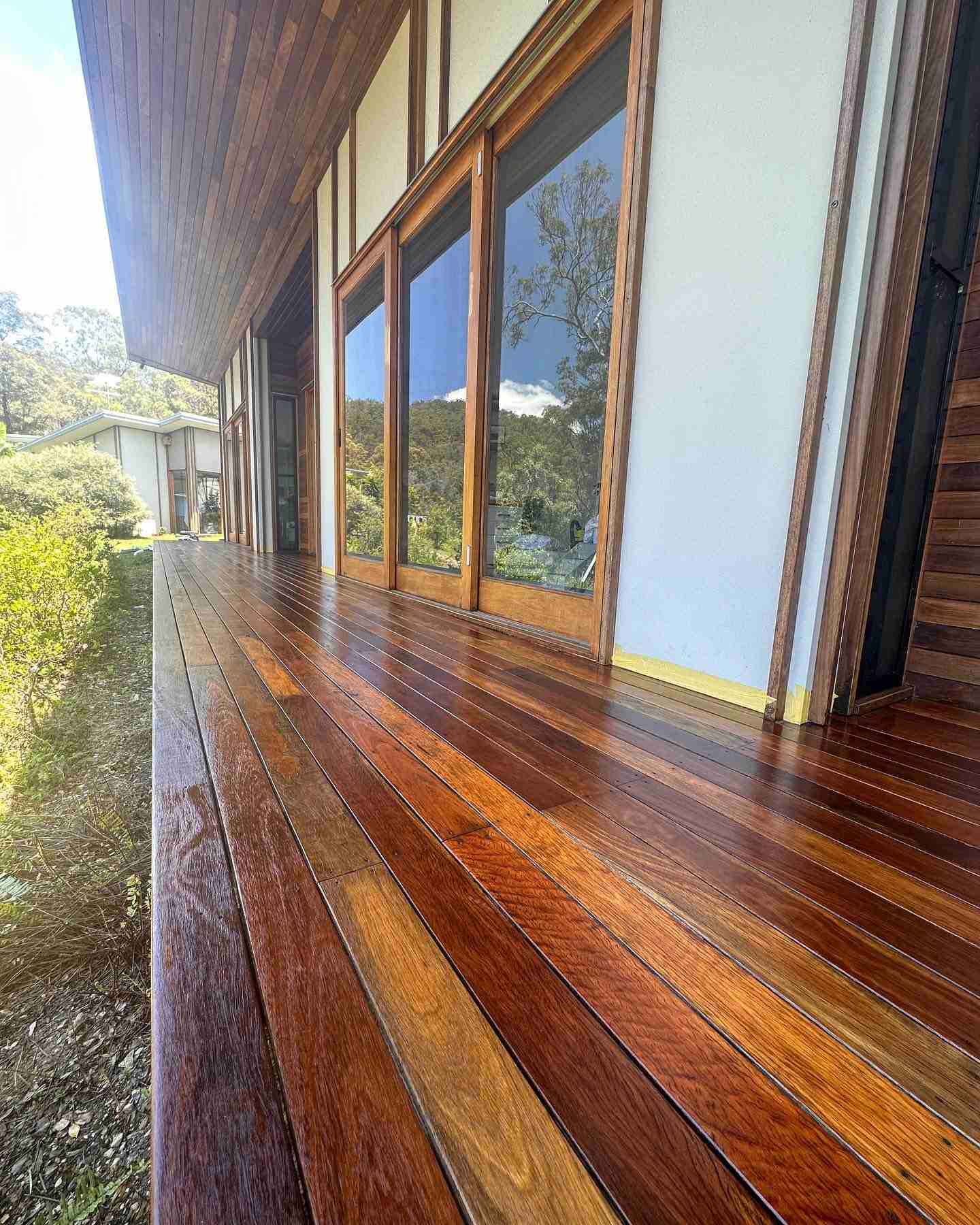Close-up of oiled timber deck boards along a row of glass doors