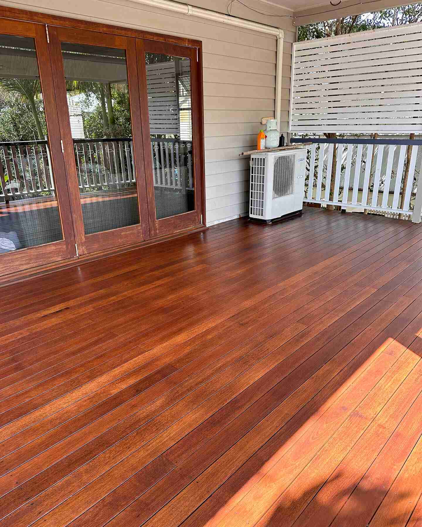 Oiled timber deck outside timber-framed doors with a white privacy screen